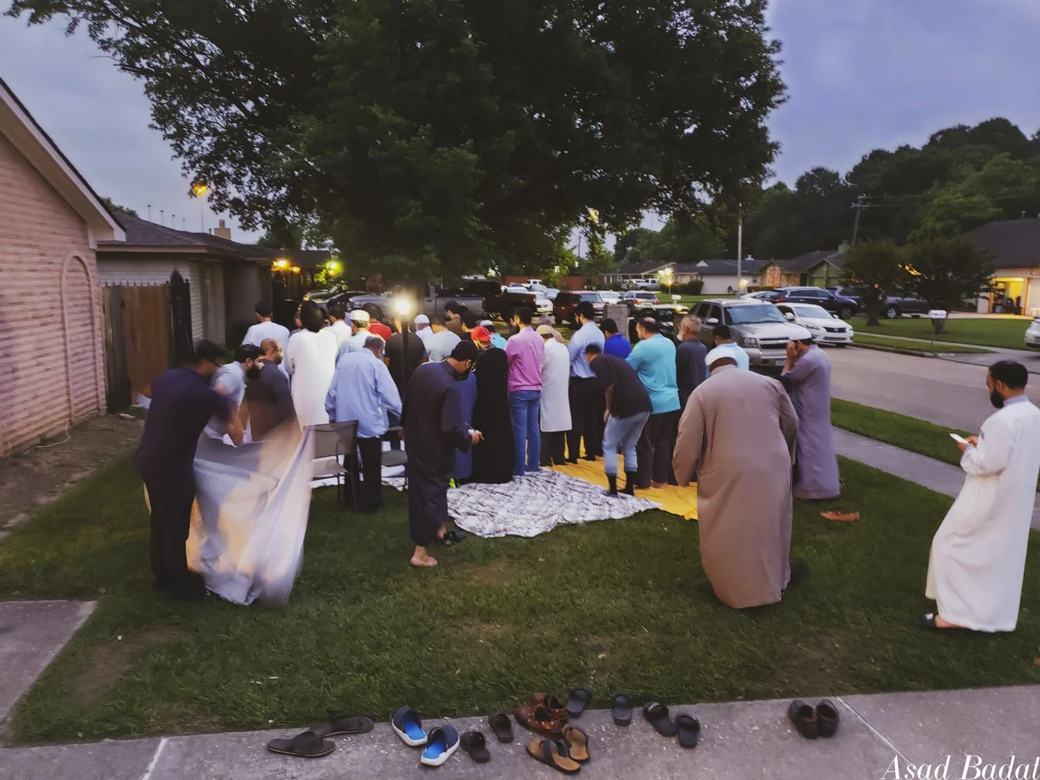 Shoes line the pavement while everyone stands on the sheets barefoot.