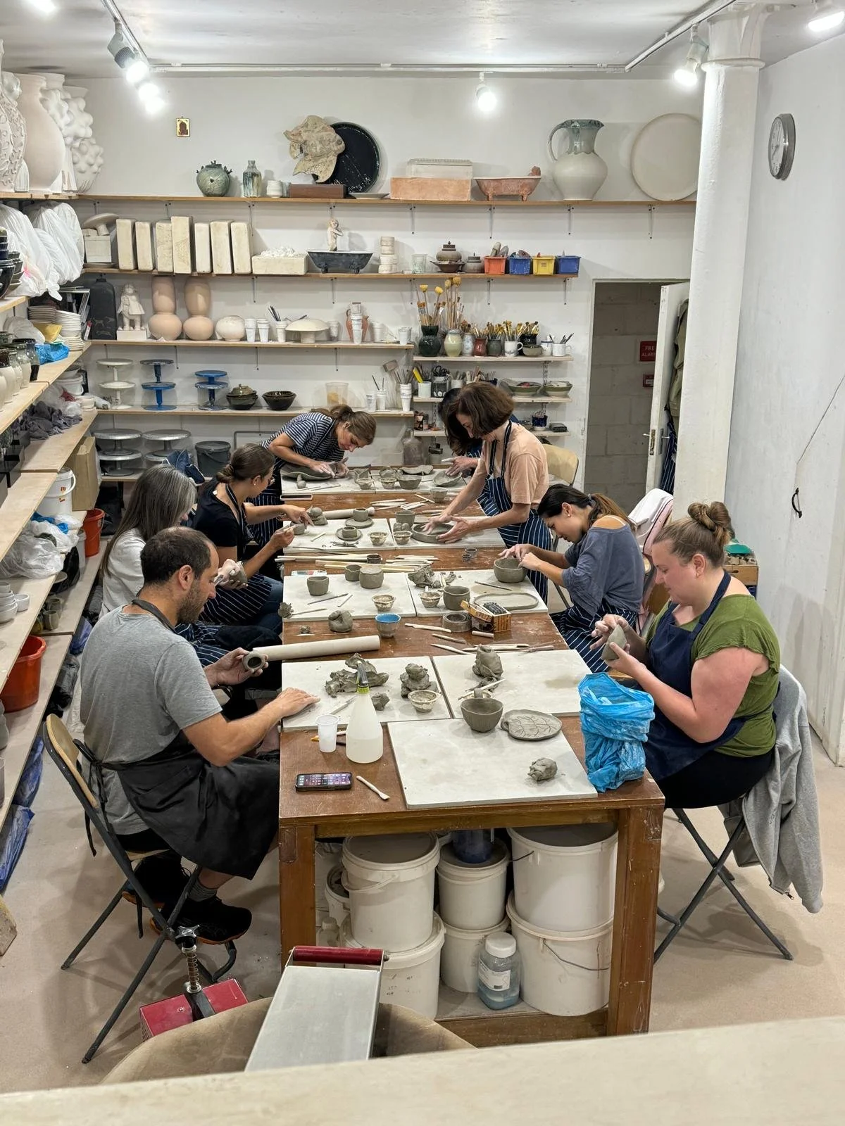Students working on ceramic pieces at a table during a pottery class in West Hampstead studio