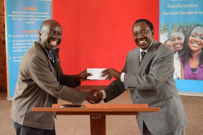 The Daystar University Alumni Association (DUAA) Board Chair Mr. Omeno Suji presents the Vice Chancellor with a check on behalf of the Class of 1996, who pooled their resources to fund two student scholarships. 