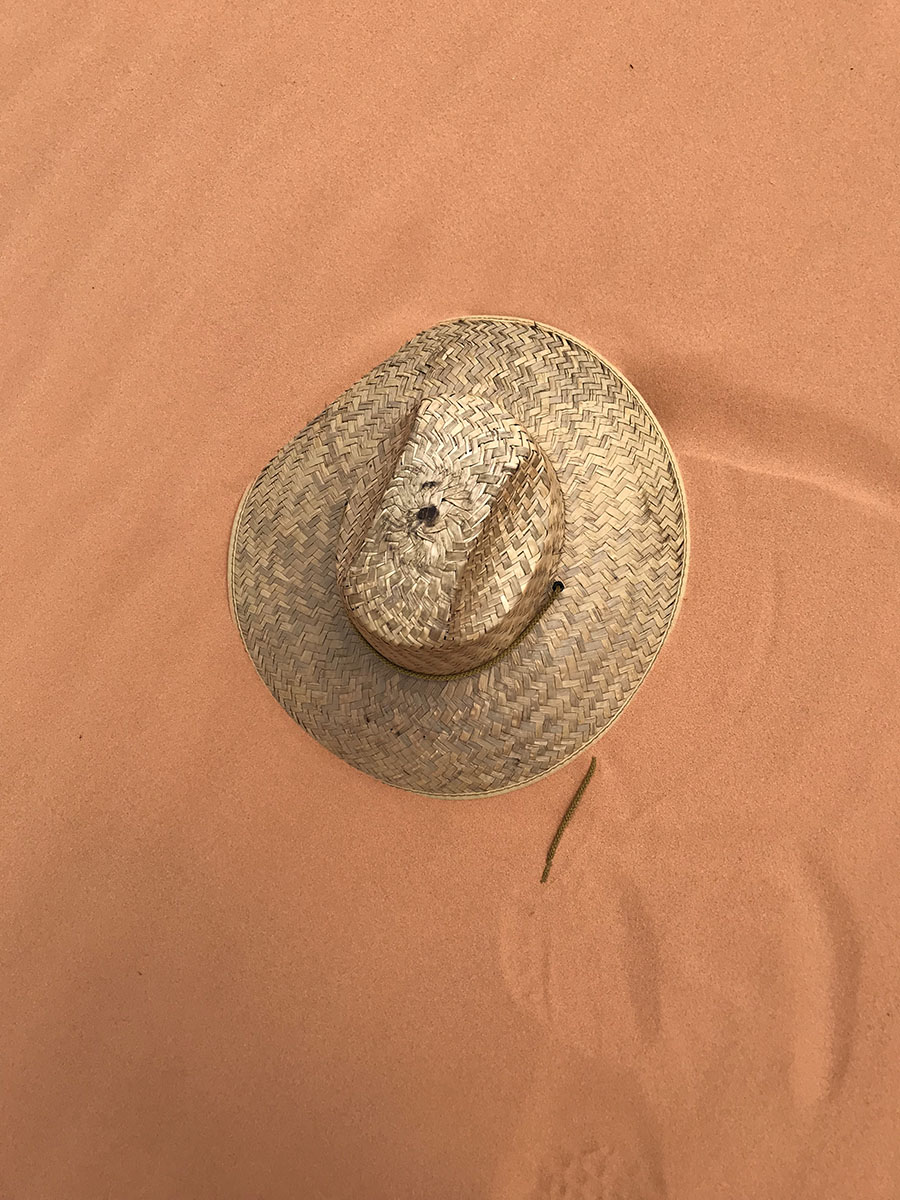 Sand holding my swept away hat for me!