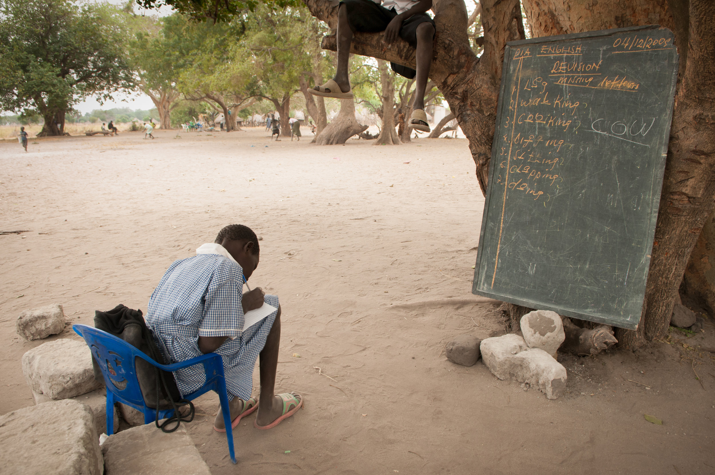 An elementary school student in Duk Payuel practices English as a classmate rests in the tree above.