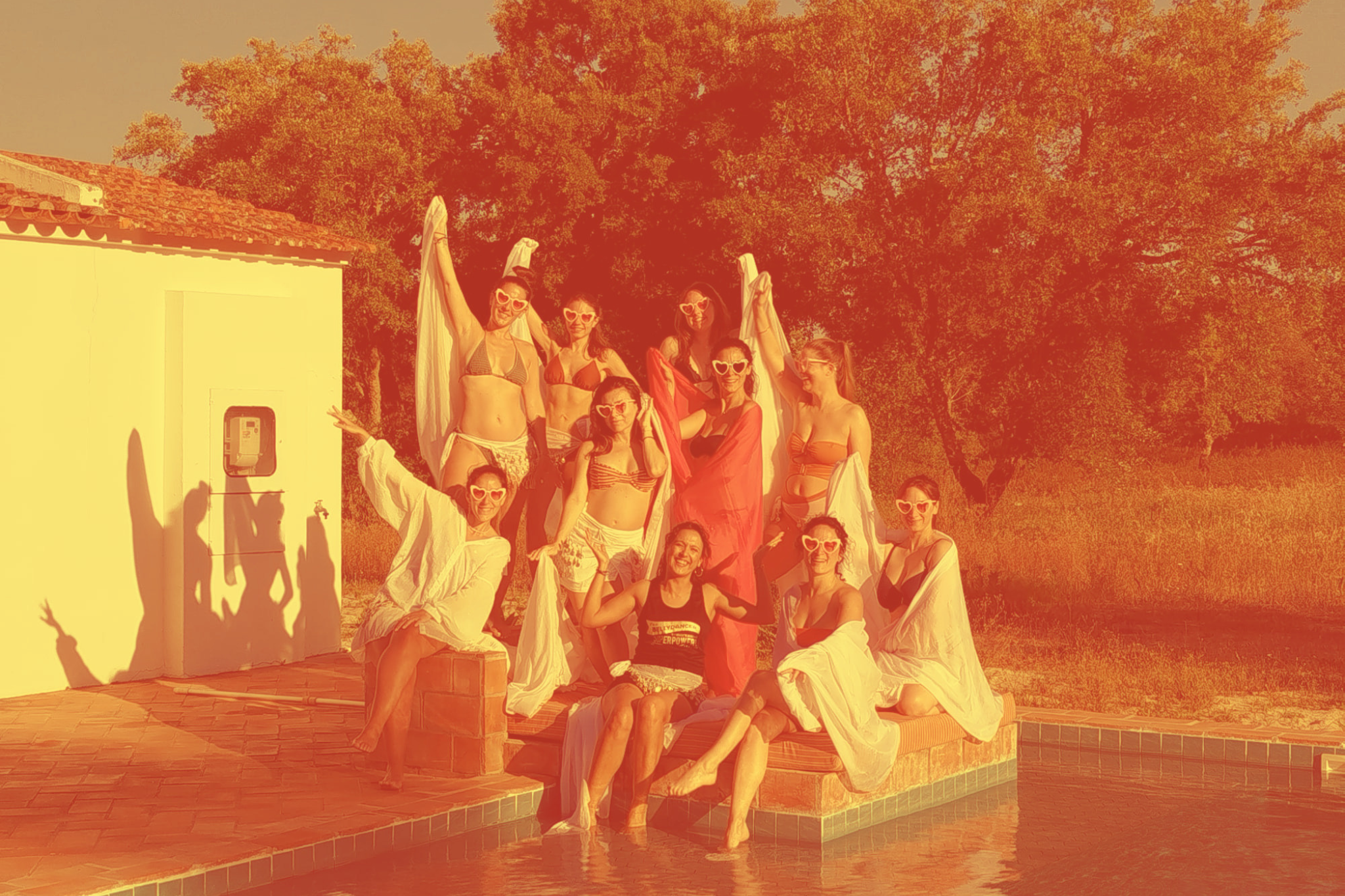 Grupo de mulheres dançando em uma sala de ginástica, usando roupas pretas e saias com detalhes de miçangas, em uma aula de dança tribal ou similar.