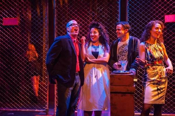 Two British couples enjoy a laugh in a theatre bar in London in Silva Semerciyan’s Turning Tricks , directed by Erin Gilley (L to R: Naseem Etemad, Lawrence Radecker, Denmo Ibrahim, Adam Roy, Emily Keyishian).