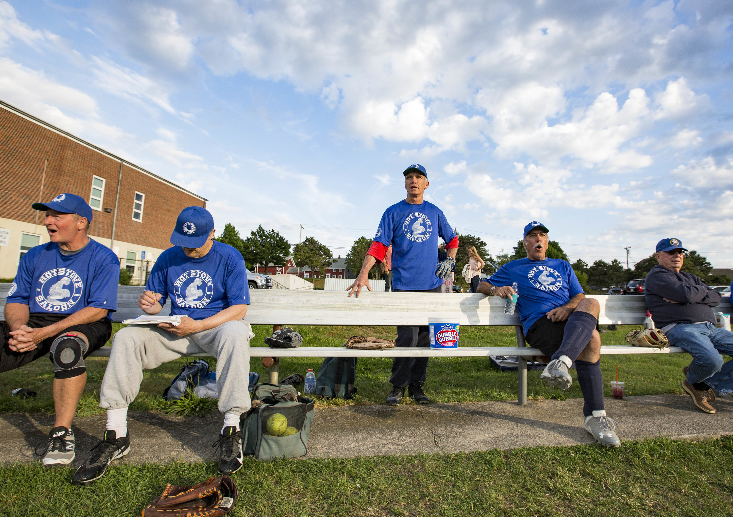  Stephen Akerman, center, watches his teammates of the Hot Stove Saloon from the bench during their game against the Mid-Cape Door on June 27, 2017. Akerman is the youngest player in the league at 56. 