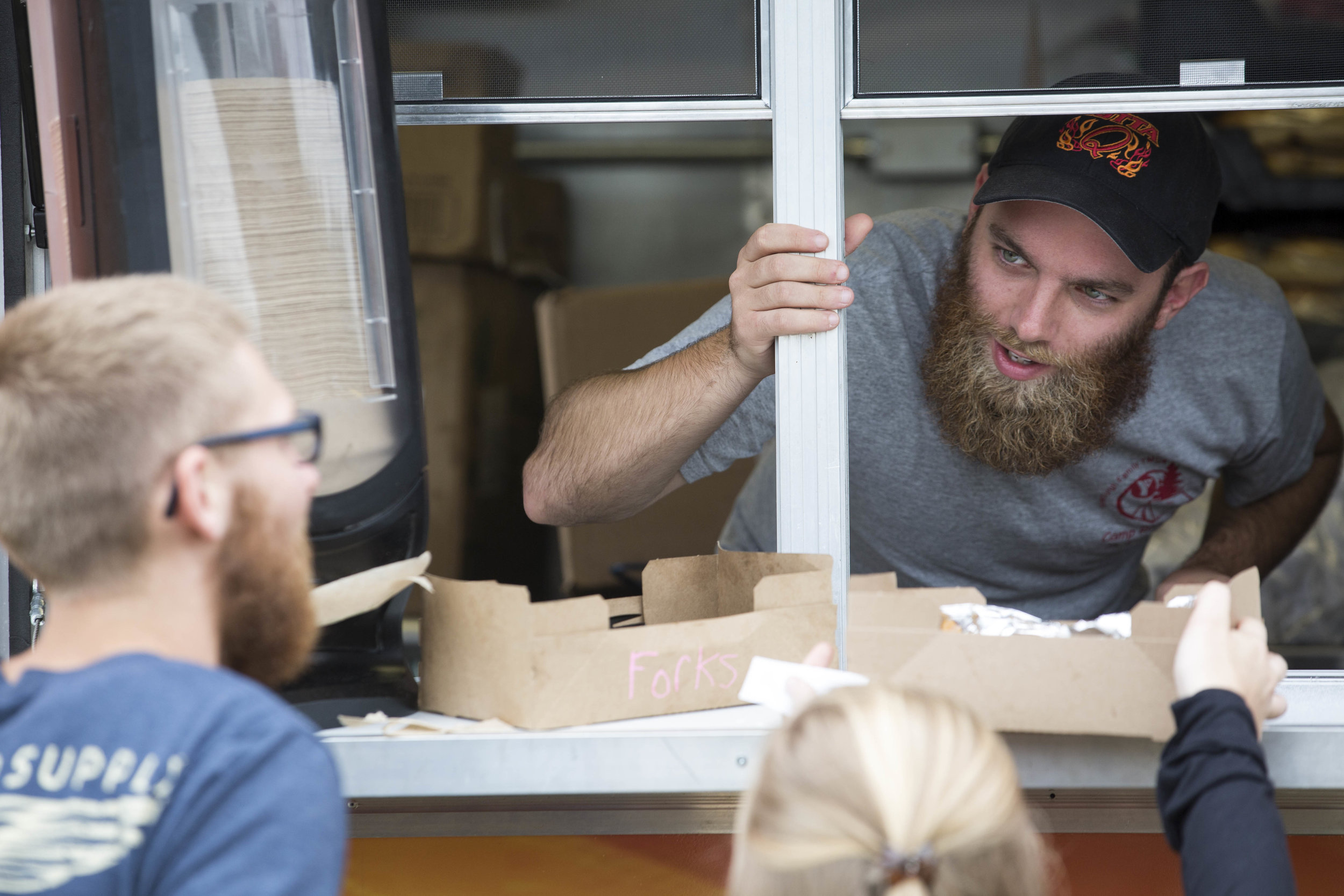  Cape Cod Times reporter Ethan Genter serves food to Josh Kilmonis and Elizabeth Prest from the GottaQ Barbecue food truck on August 12, 2017. 