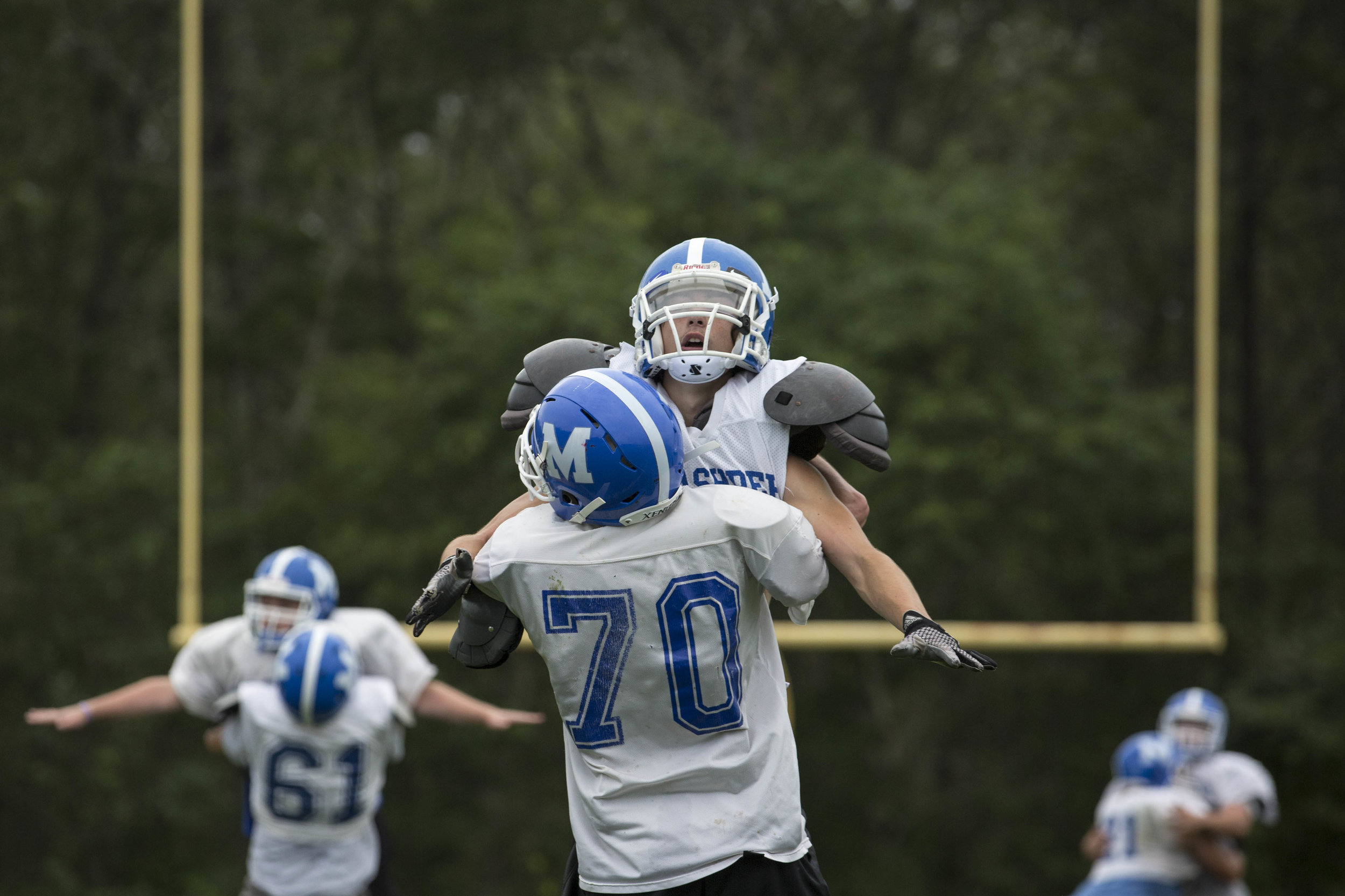  A Mashpee High School football player lifts his teammate into the air during a tackling drill at practice on August 22, 2017. 