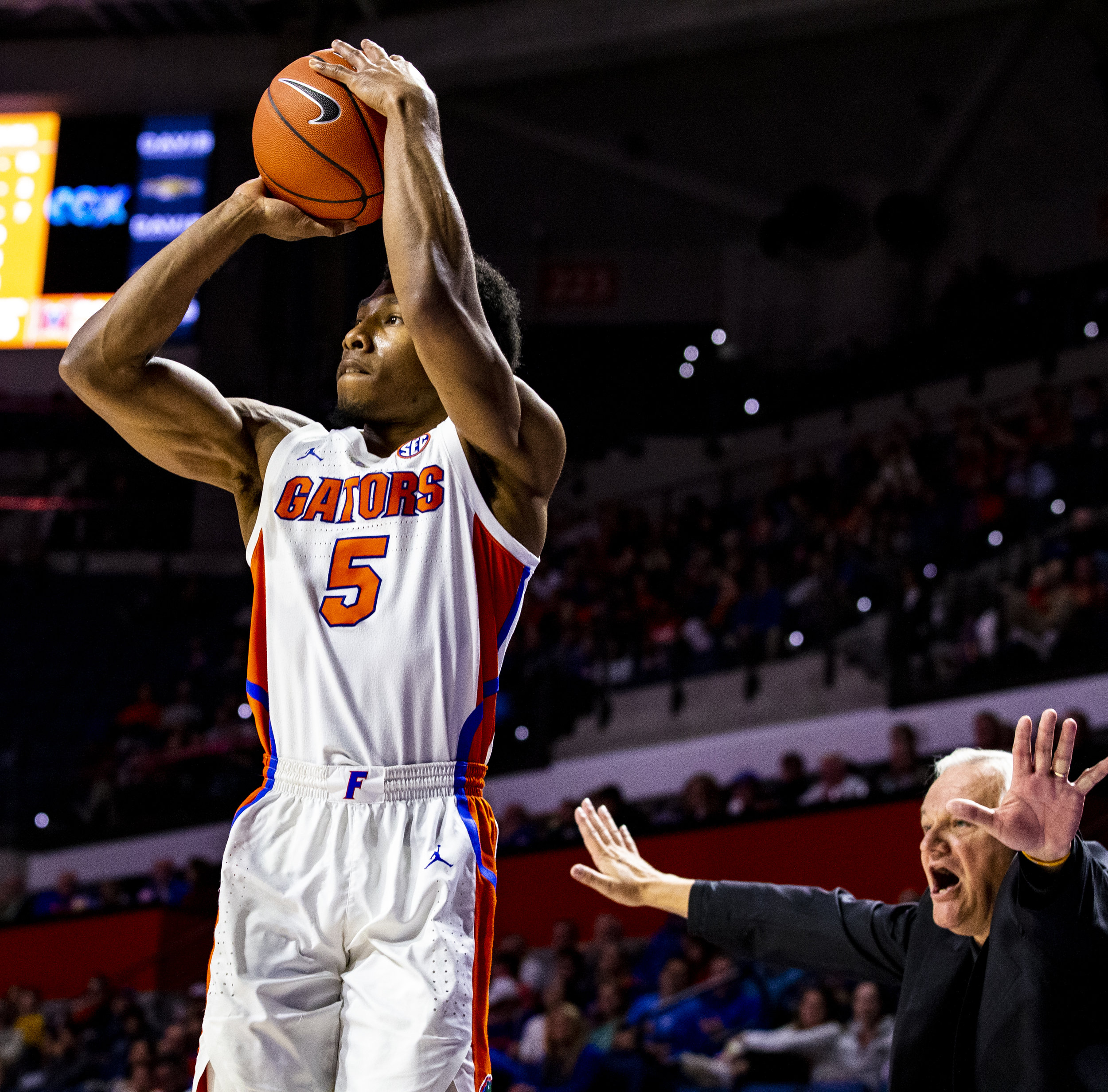  Florida Gators guard KeVaughn Allen (5) shoots a three-pointer as Mercer Bears head coach Bob Hoffman yells behind him during the Florida Gators home game against the Mercer Bears on December 18, 2018. The Florida Gators won 71-63. 