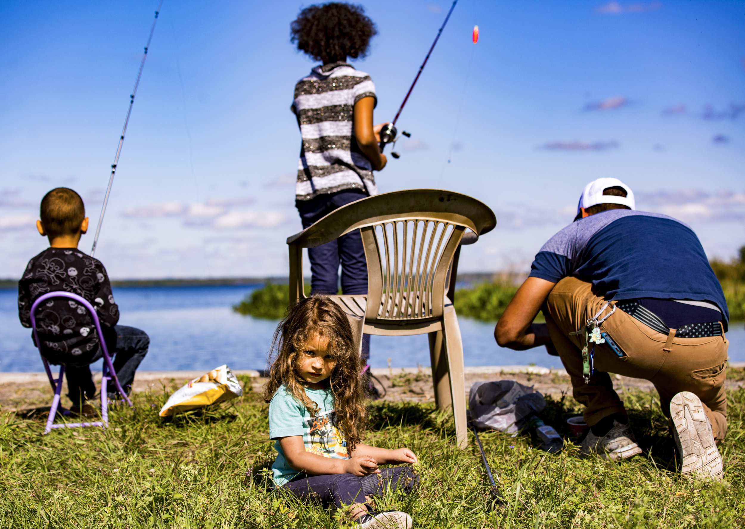  Evelyn Steelem, 3, sits in the grass as Mylo, 5, Ebony, 10, and Mike Steelem fish behind her at Paynes Prairie along US 441 on April 2, 2019. 