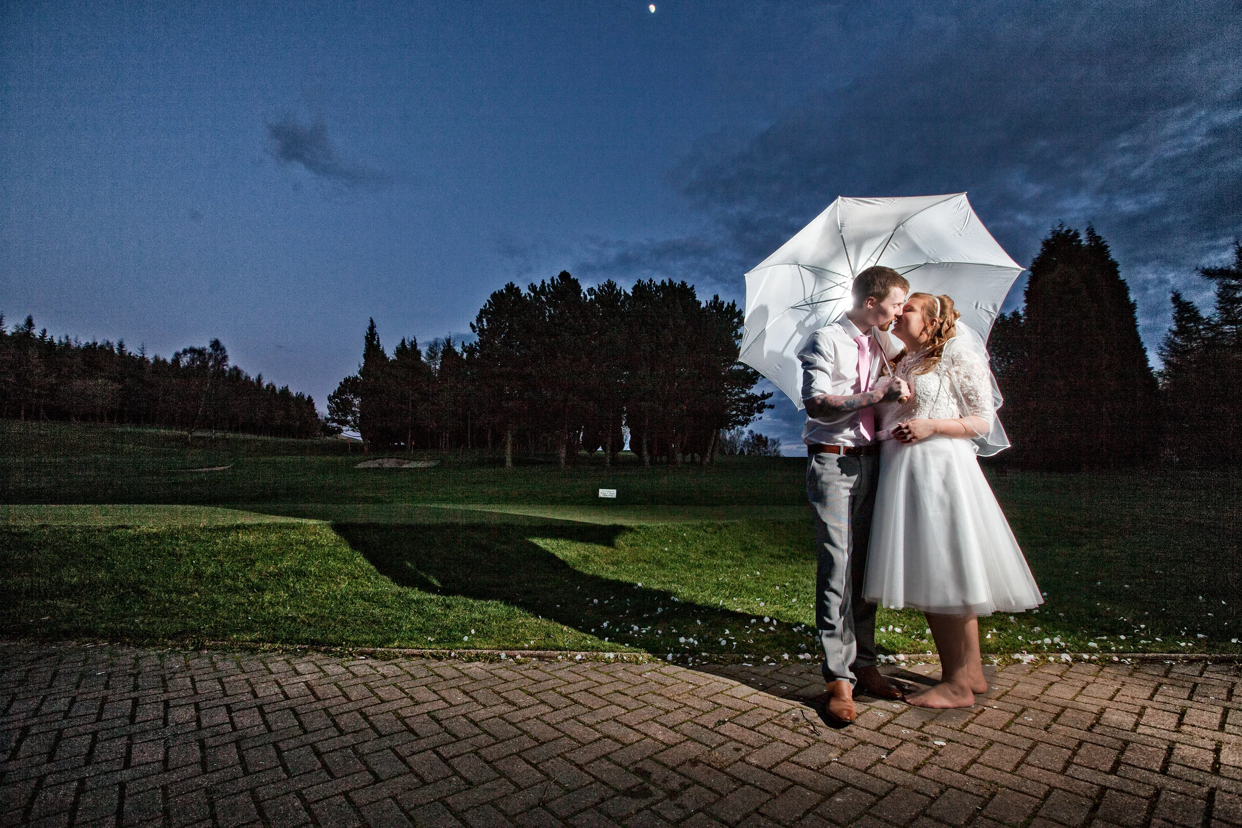 Bride and groom on their wedding day ,with umbrella.Shot at Gyll golf club near Skipton
