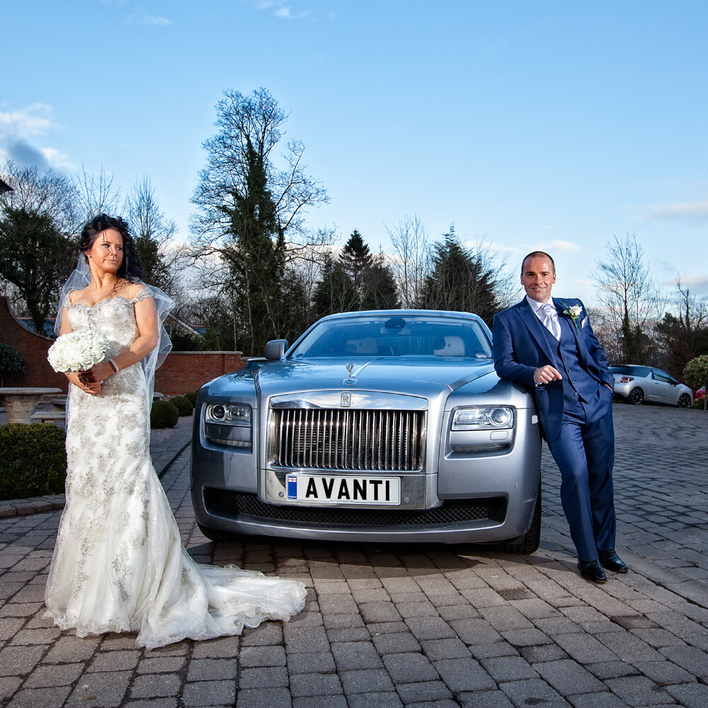 Bride and Groom pose infront of Rolls Royce Wedding Car at Eaves Hall near Clitheroe.
