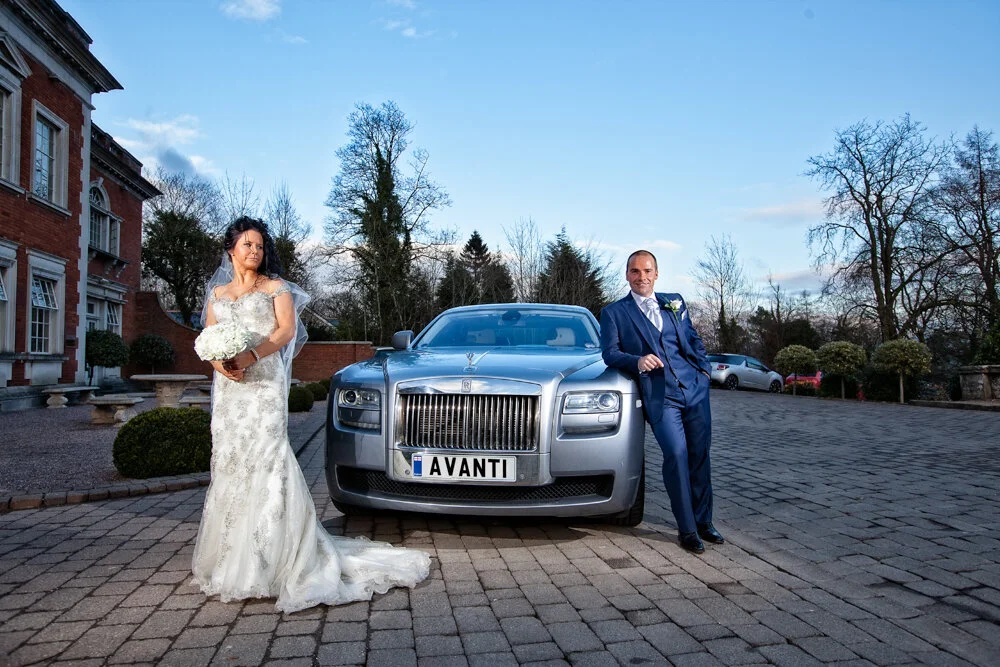 Newlyweds pose with their Rolls Royce wedding car at Eaves Hall,Clitheroe.