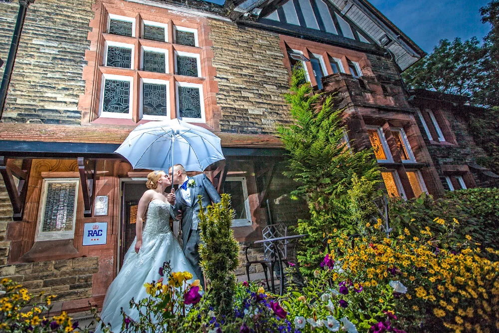Newly weds pose with umbrella outside The Whitehall Hotel,Darwen,