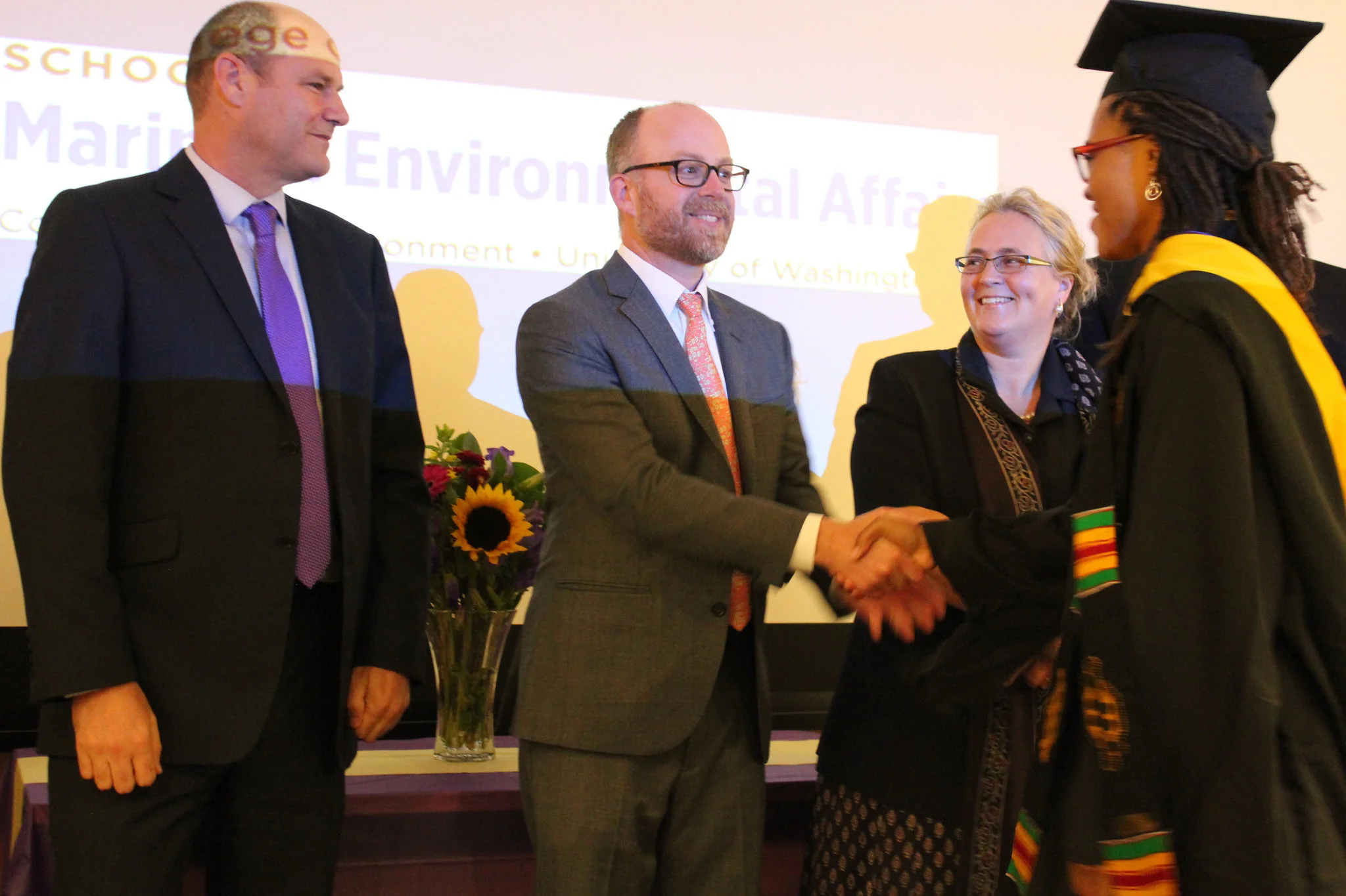 Jillian Lyles shakes Professor Kelly's hand as Professor Dolsak and Professor Allison look on.