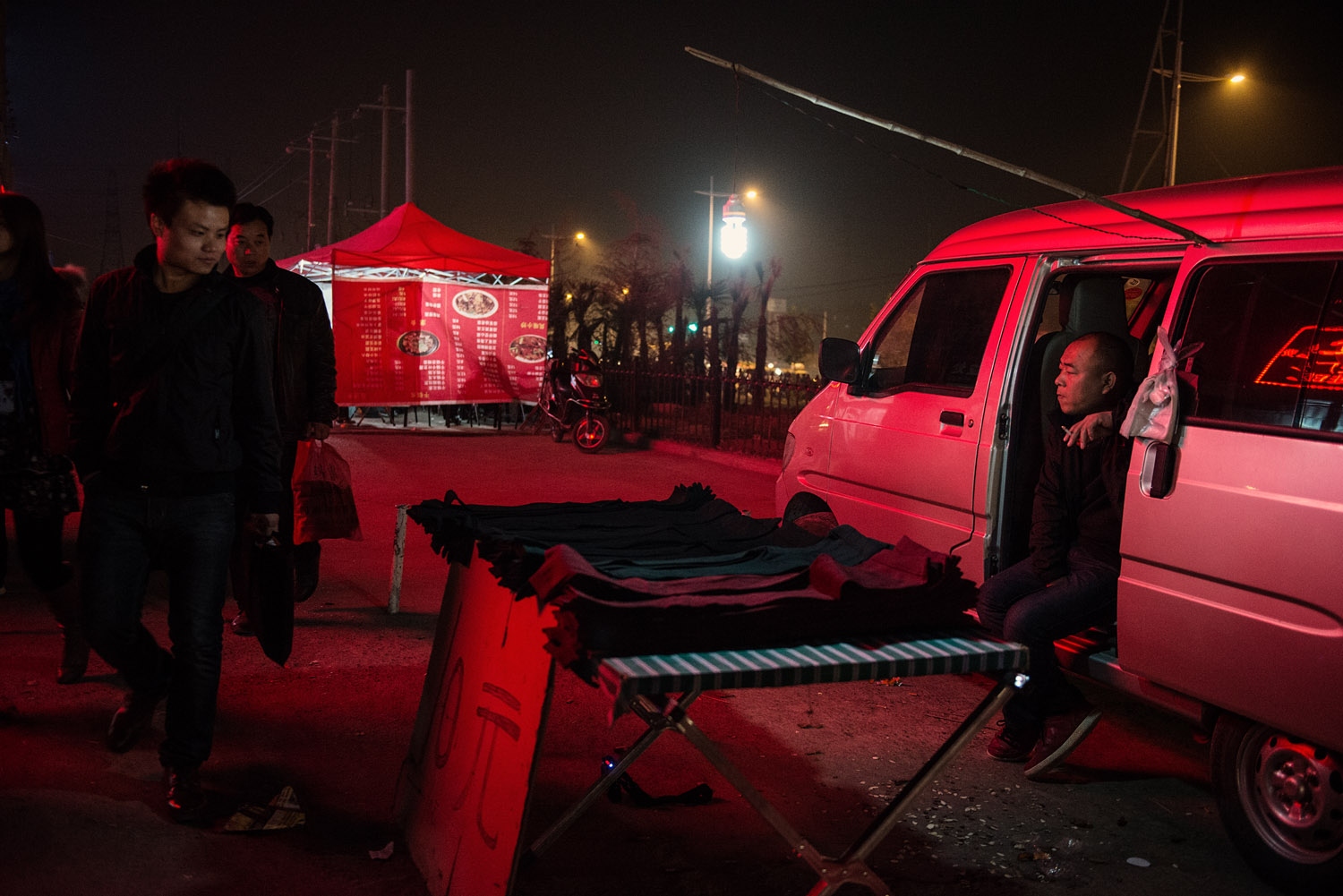 Foxconn workers passing by a cloth vendor. The sudden influx of young workers in what was a rural suburb of Zhengzhou has attracted many small businesses ran by locals and catering to the workers needs.