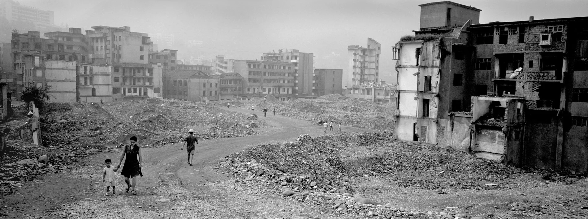 Inhabitants of Gaoyang walking by the razed buildings of the old city. Positionned by a subsidiary of the Yangtze, the city got flooded in the summer of 2006.