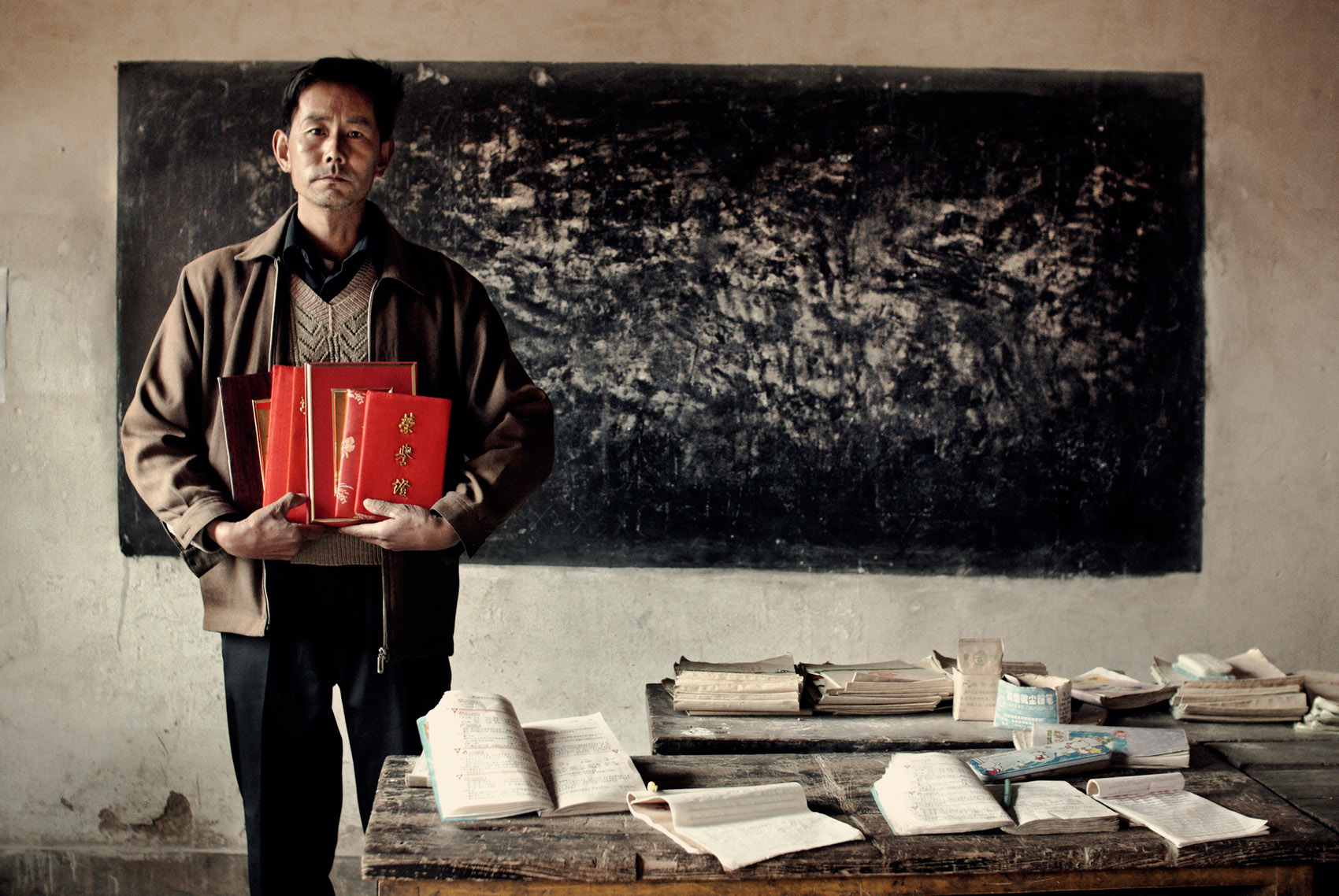   Lei Shui Xiang, headmaster of Guan Shan (Gansu) primary school, holding awards. Devoted to the children, covered with academic honors, his monthly income of RMB 150 hasn’t changed in 25 years, in spite of repeated request to have his status changed