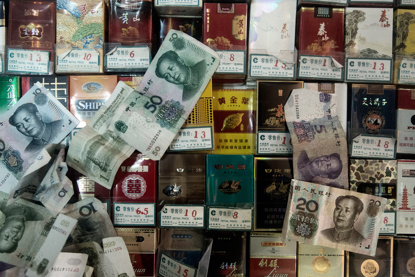 Bank notes on packs of cigarettes at a retailer in Beijing. The tobacco industry in China is state-owned and contributes annually to close to 10% of the central government revenues. 