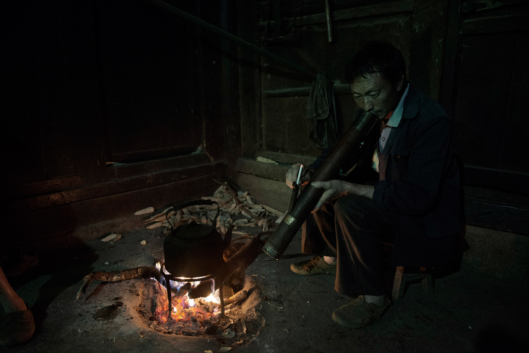 In Guangxi Province a farmer smoking a cigarette through a water pipe.