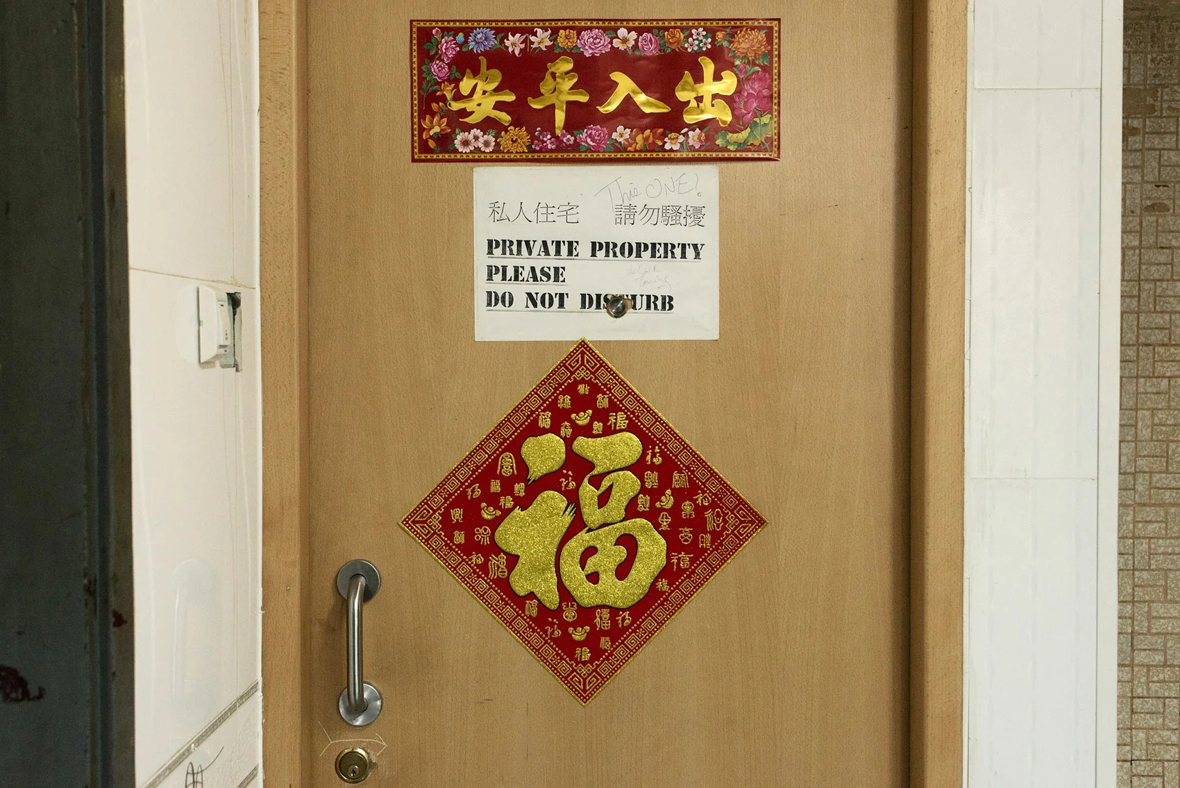 Inside the Chungking Mansions, the door of a private apartment where a Chinese family is living. Most of the residents of the Mansions are transient workers and hostels guests. However a few families live there in spite of the building bad reputation..