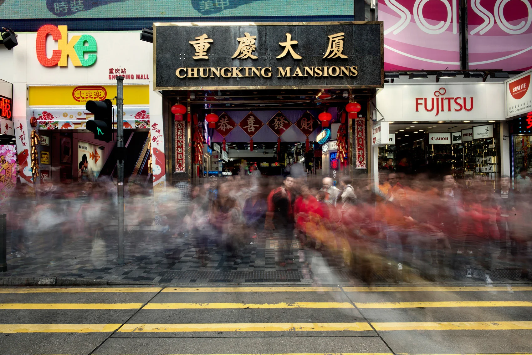 Pedestrians walking in front of the Chungking Mansions. The Mansions are situated on Nathan Road also called the "Golden Mile", a central street of Hong Kong heavy with traffic and popular with tourists. Stores lining Nathan Road make great business catering to the need of its crowds..
