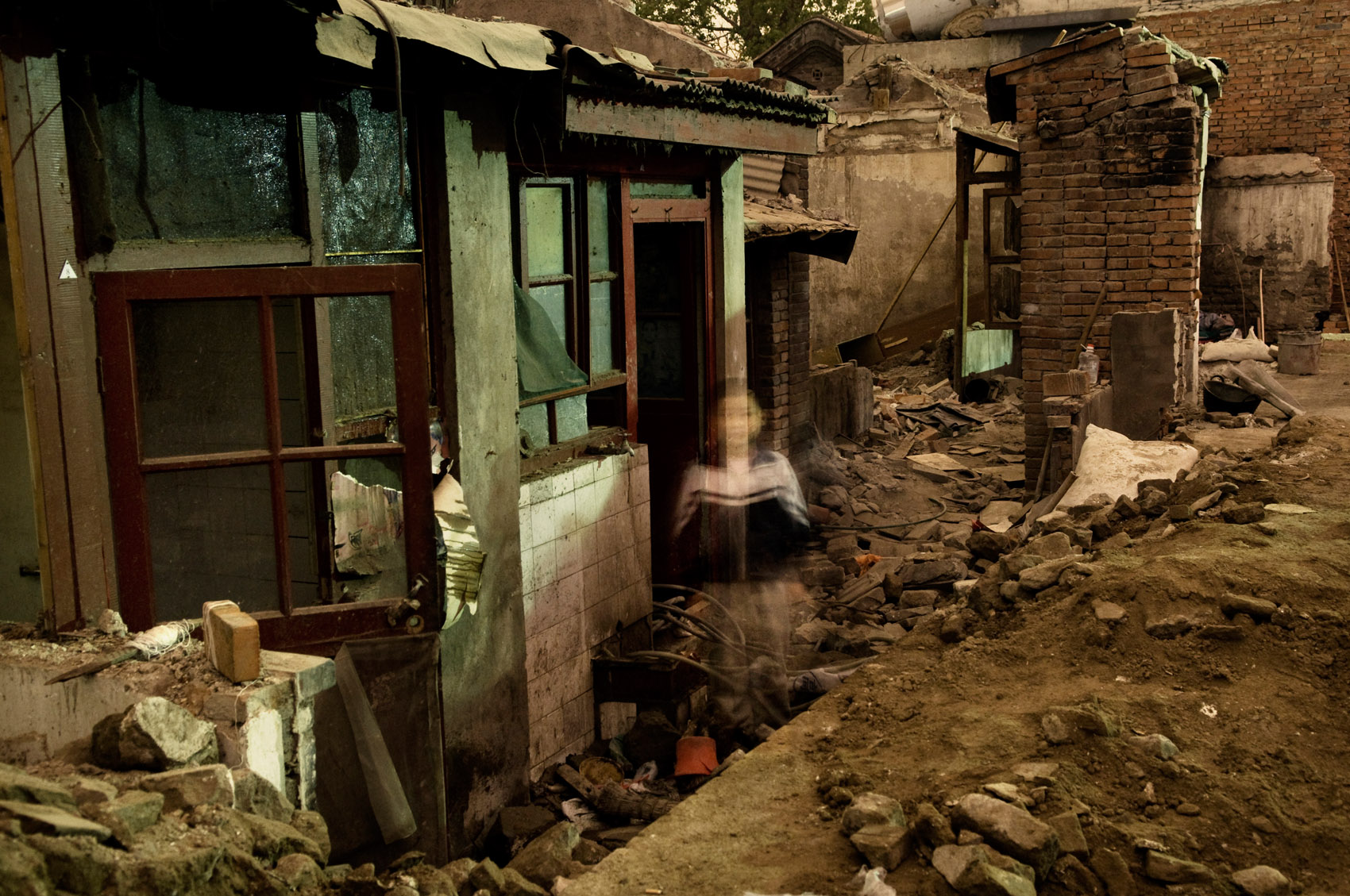 A migrant's child standing in the ruins of Beijing traditional housing near the Forbidden City. The destruction of old neighborhoods including many architectural treasures is one consequence of China's urbanization. 