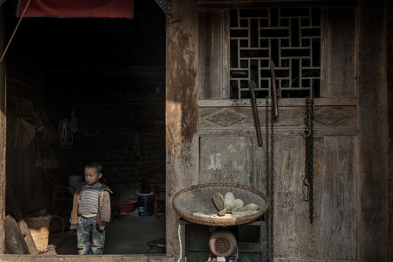 4 years old Ting Rui, Hailian cousin, standing at the door of his grand parents home on a day he and his sisters were left alone at home. Ting Rui's father works hundreds of miles away, while is mum has disappeared.