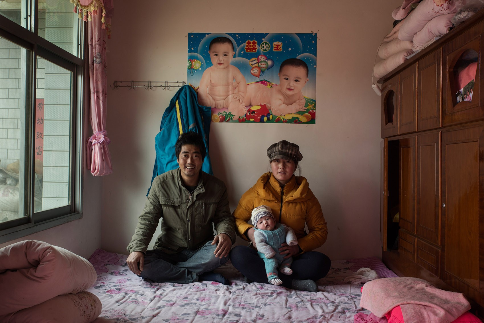 Anjiawan village Peng Yongjie, 38 yo, with his wife 30 years old Di Jinfang and their 40 days old daughter. Peng And Di have been trying to have a baby since they got married 8 years ago. They have sought help from local private clinics with no success and at mounting costs. Eventually they went to a hospital in the provincial capital Xian, where they were quoted 20,000RMB (US$ 3,200) for an artificial insemination. At the time Peng and Di only had 3,000 RMB in savings. For four years Peng and Di saved money to eventually be able to pay for the operation last year. The first attempt was successful. They now want to have another baby, a boy. The poster on the wall was put up 7 years ago. Peng is a construction worker and makes about 100 CNY (16US$) a day. The picture was taken the day before Peng's departure for work after the Chinese New Year break. 
