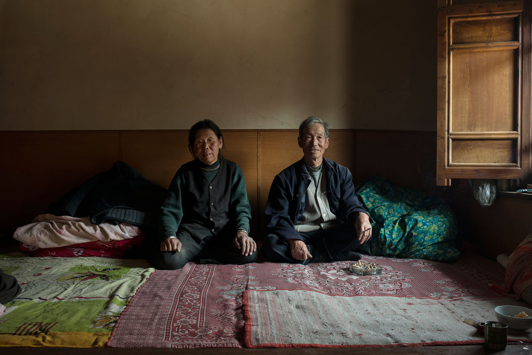 Yujiaping Village Yu Zhanglai (67) with his wife Dong Juming (67). 60% of the population of Yu Jiaping has moved down to the new village but a new house costs 200K RMB (32,000 US$) and they can't afford to move. A new road has been built between the old and the new village. Each family contributed 1,000R RMB to the construction but they are too poor to contribute.