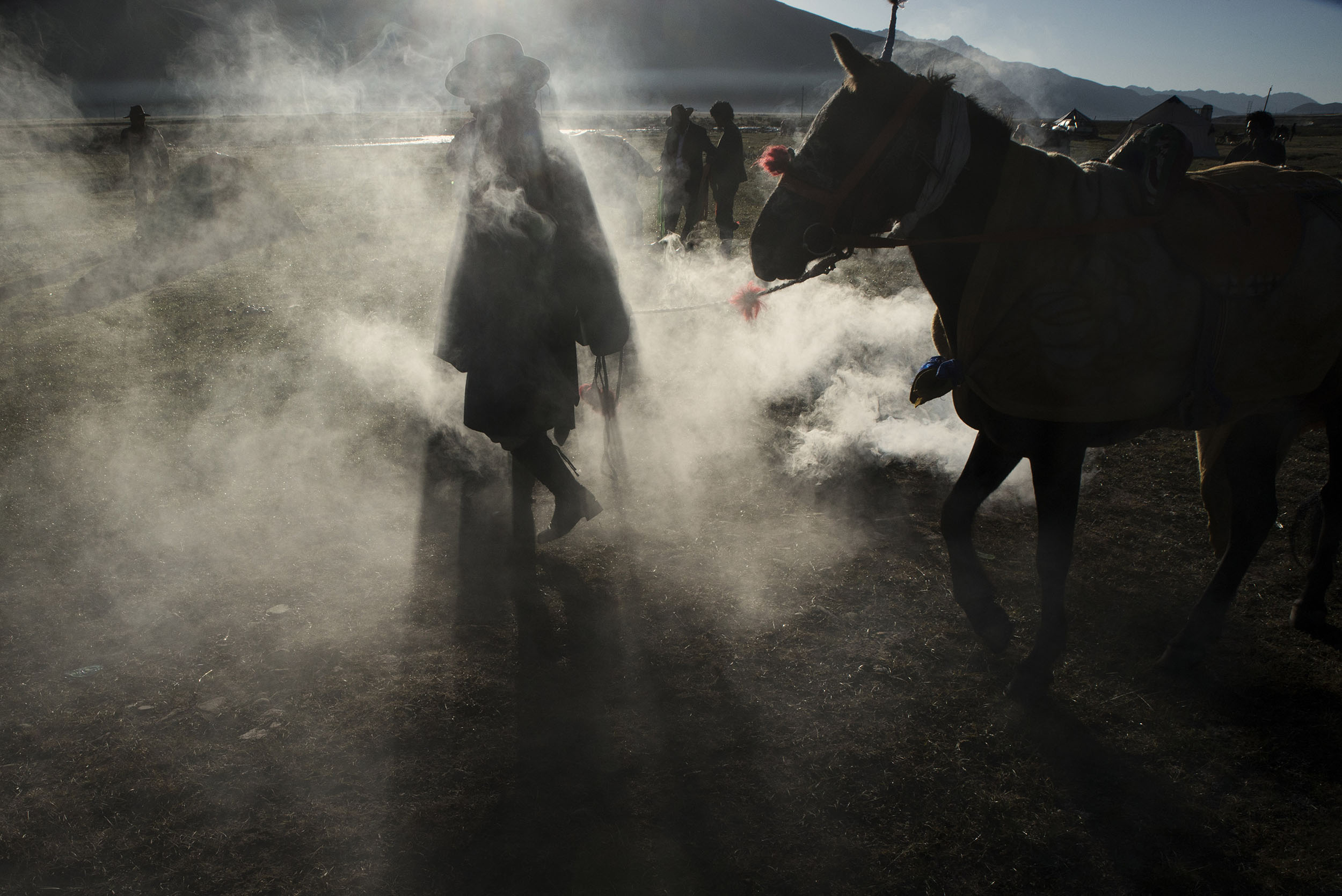 At sunrise, a Tibetan horseman walks his horse through the smoke coming from a juniper fire, a cleansing and strengthening ritual, before taking part in a horse race at Yushu horse festival. Nomadism is a pillar of Tibetan culture. The governement resettlement policy put this culture at risk as thousands of former nomads are forced into a sedentary lifestyle for which they are ill-equipped.