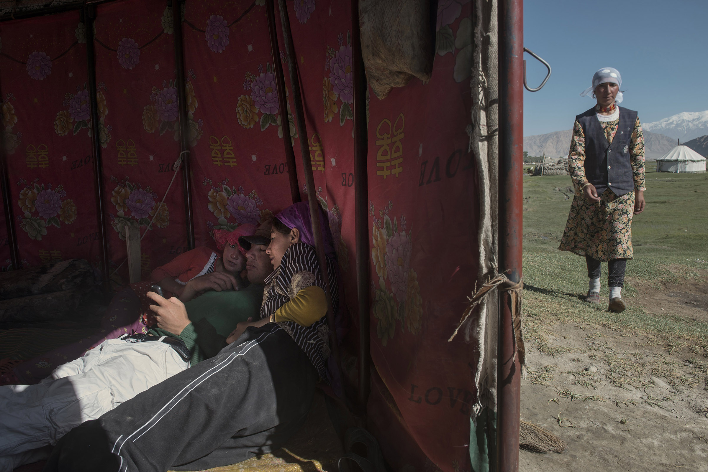Young Tajiks, playing with a smartphone made of wood and felt, in the grassland near Tashgurkan (Xinjiang). In spite of the government efforts to curtail nomadic pastoralism, this family moves to the grasslands every summer. Concrete yurts have been built on the road to Tashgurkan, but haven't been used.