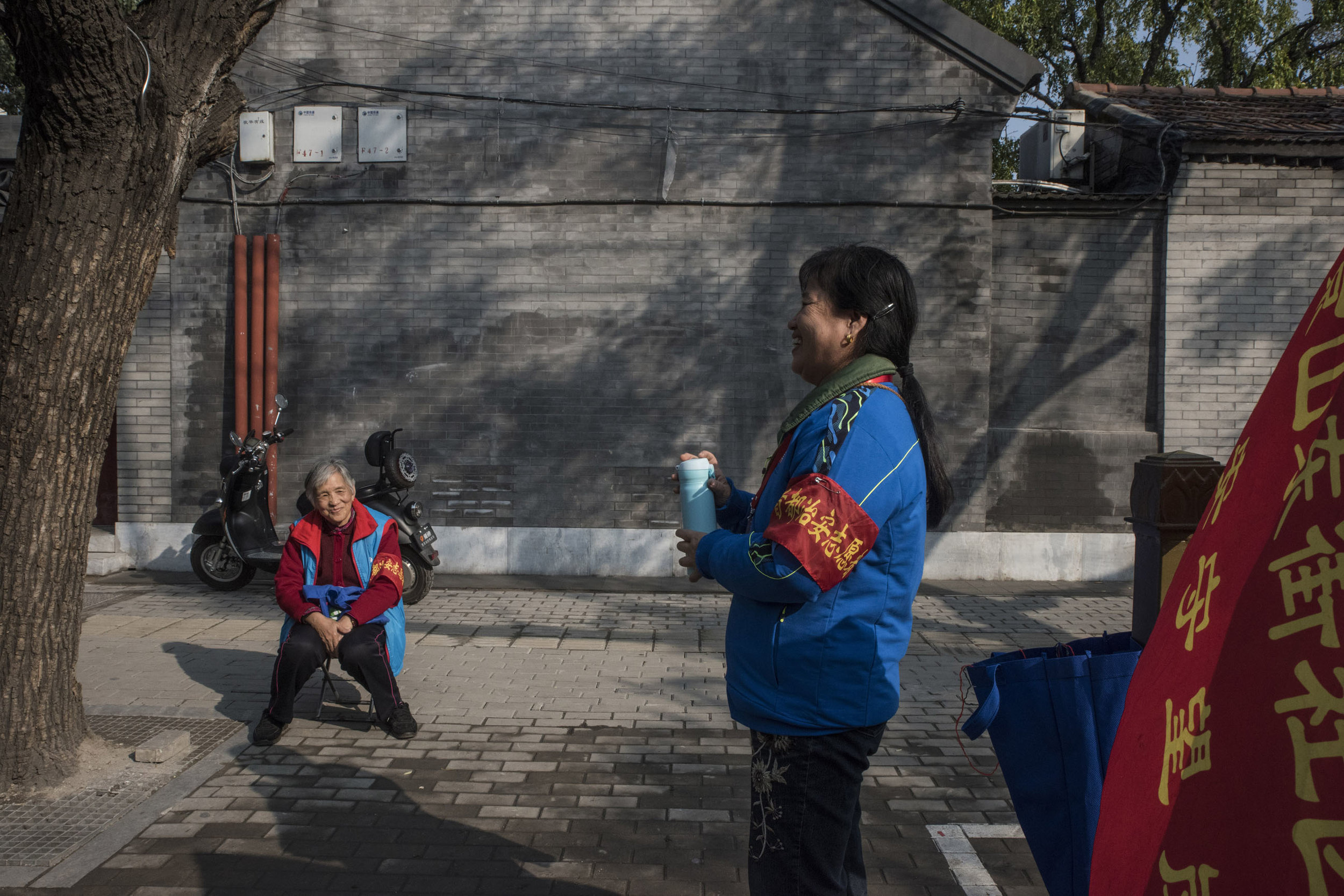 Volunteers from a neighbourhood security committee standing guard on a street of old Beijing. The Chinese government is using networks of civilians to help maintain order. These public security volunteers, eyes and ears of the local police, are mostly retired men and women whose main responsibility is to patrol the neighborhood and report anything suspicious. The district of Chaoyang in Beijing would have 190 000 such informant, about 1 for every 18 inhabitants.
