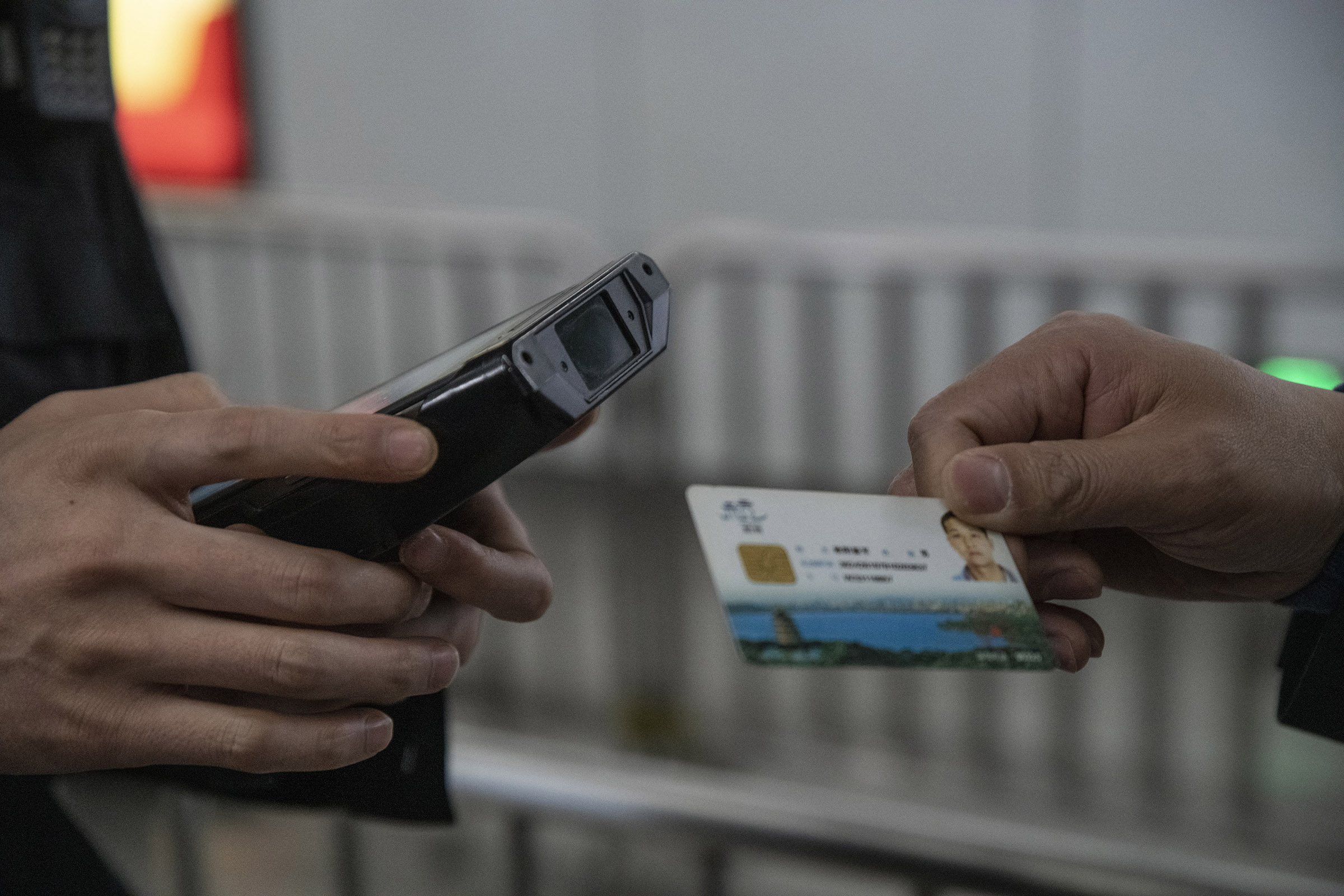 At a security checkpoint in Hangzhou, a pedestrian is handing his city smart ID card to a policeman equipped with a scanner. The card featuring a microchip, contains a large amount of private data allowing him to use city services (health, education,social security funds transport..etc) and bill payments. The card is also used for a city wide voluntary social credit rating system which so far has few users.