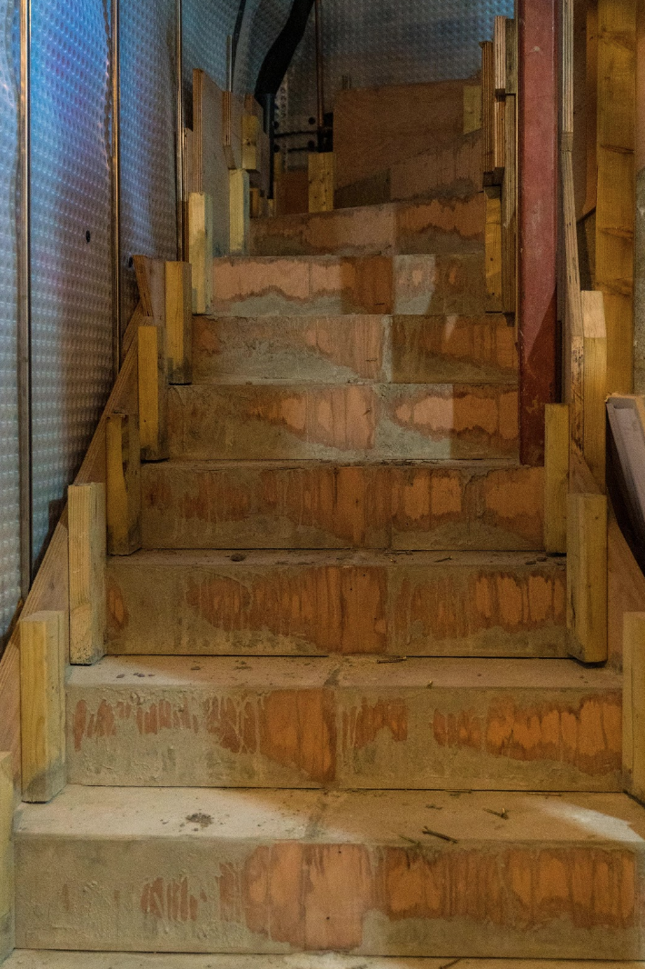 Newly poured concrete steps winding their way up from the basement through to the back entrance of the building