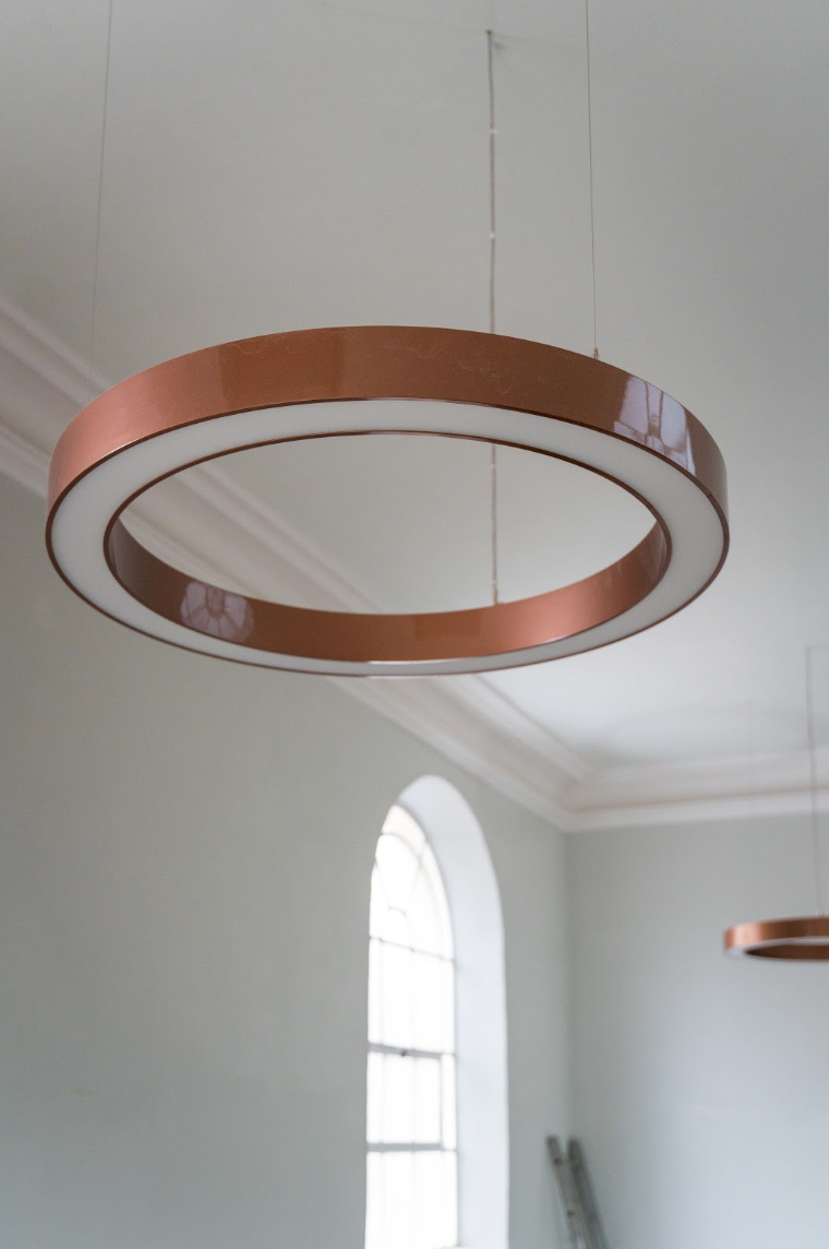 Four modern circular LED light panels hanging above the pews below.