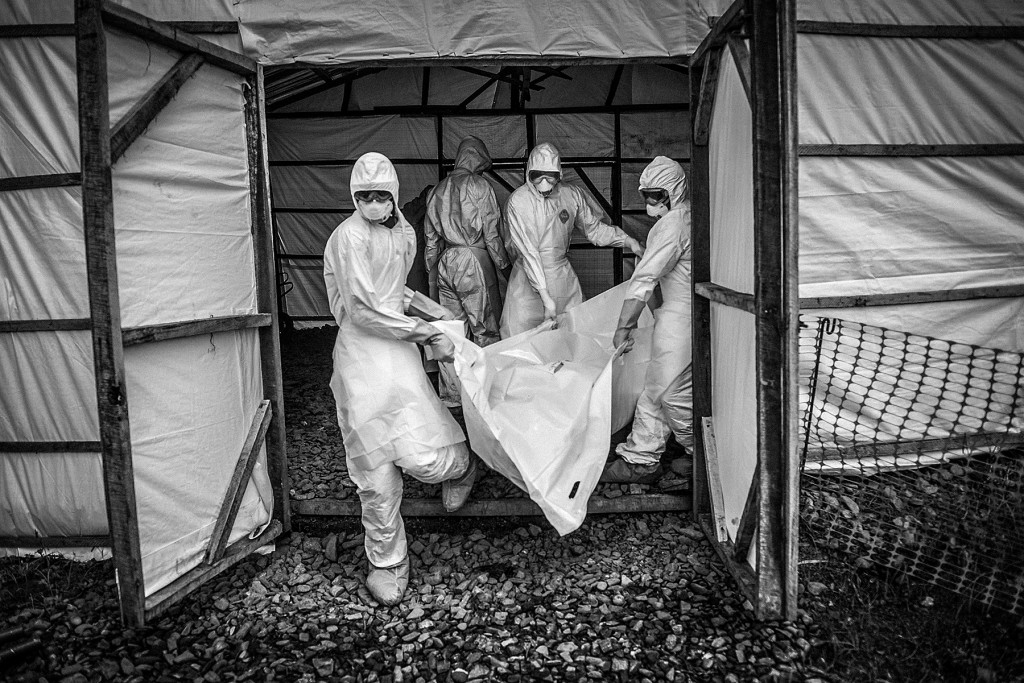 A group of volunteer medical workers carry the bodies of Ebola victims to a car in order to bury them in Kptema graveyard in Kenema, Sierra Leone, on August 24, 2014. MOHAMMED ELSHAMY/ANADOLU AGENCY/GETTY IMAGES