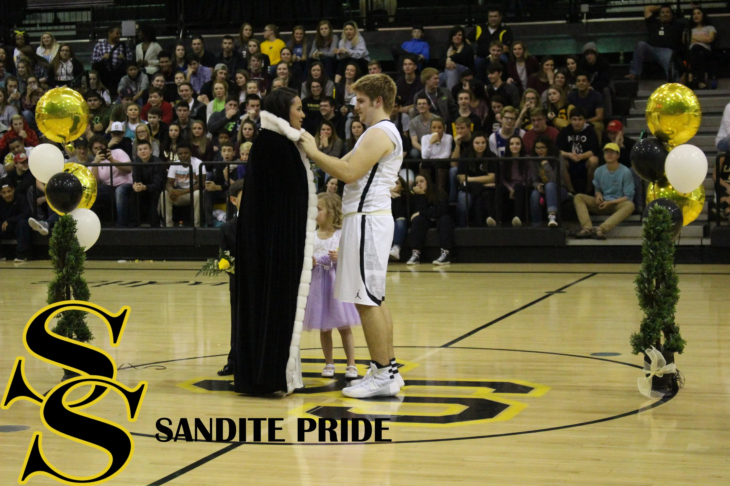 Senior Jacob Taber places the robe and crown on Scott. 