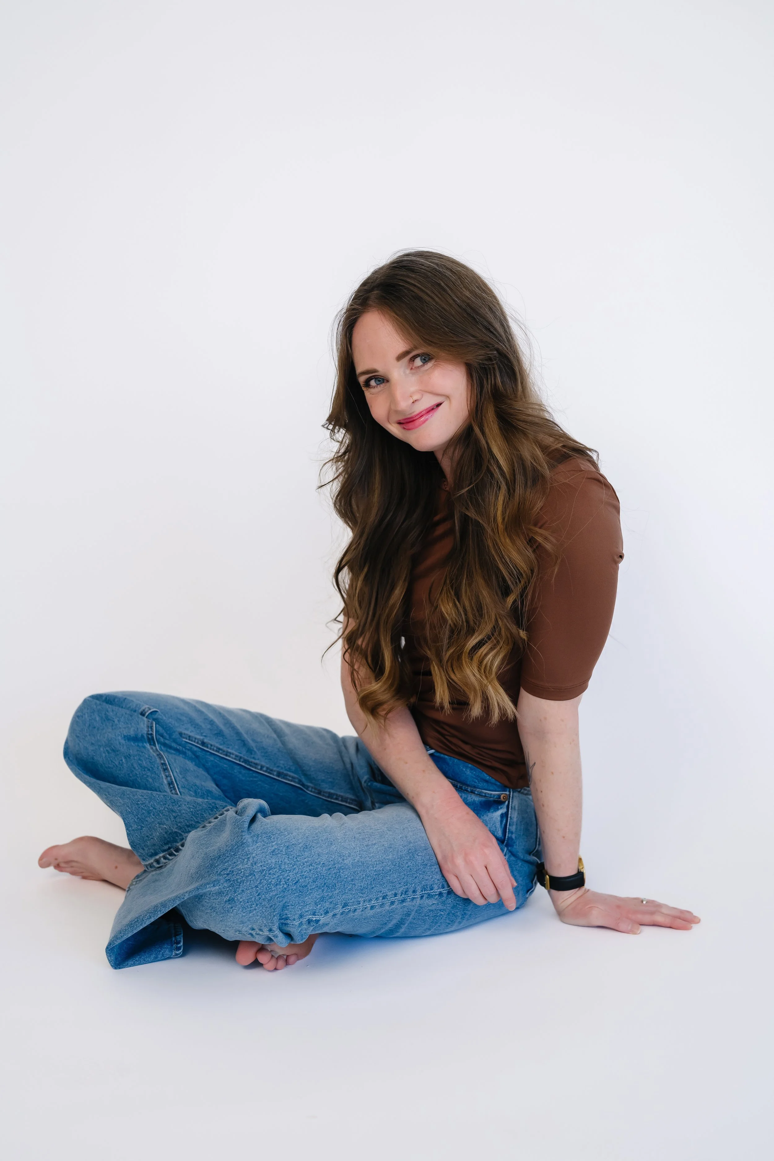 Sam Kelly in brown shirt and jeans sitting on the ground
