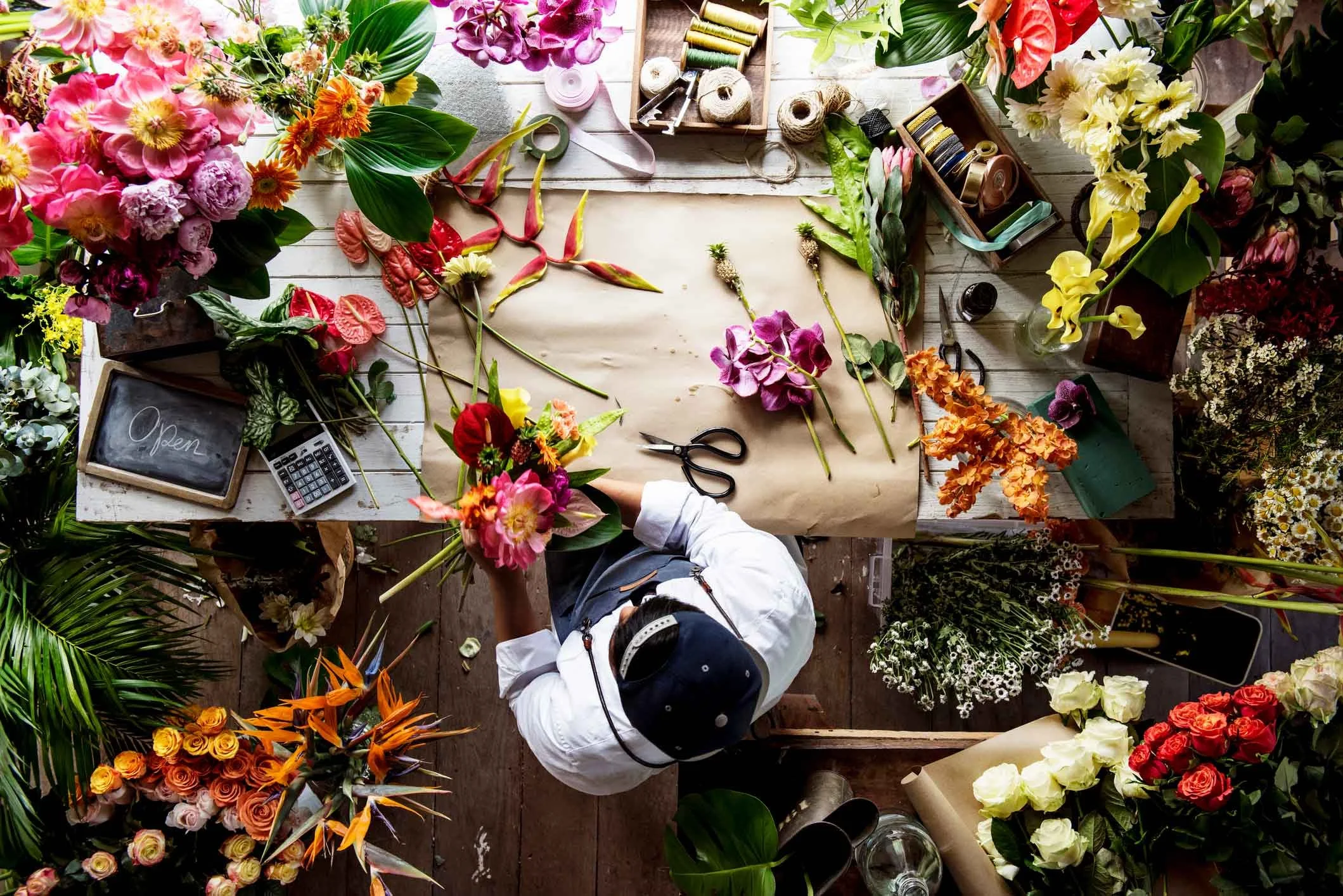 Florist working at the table that filled with colorful flowers.