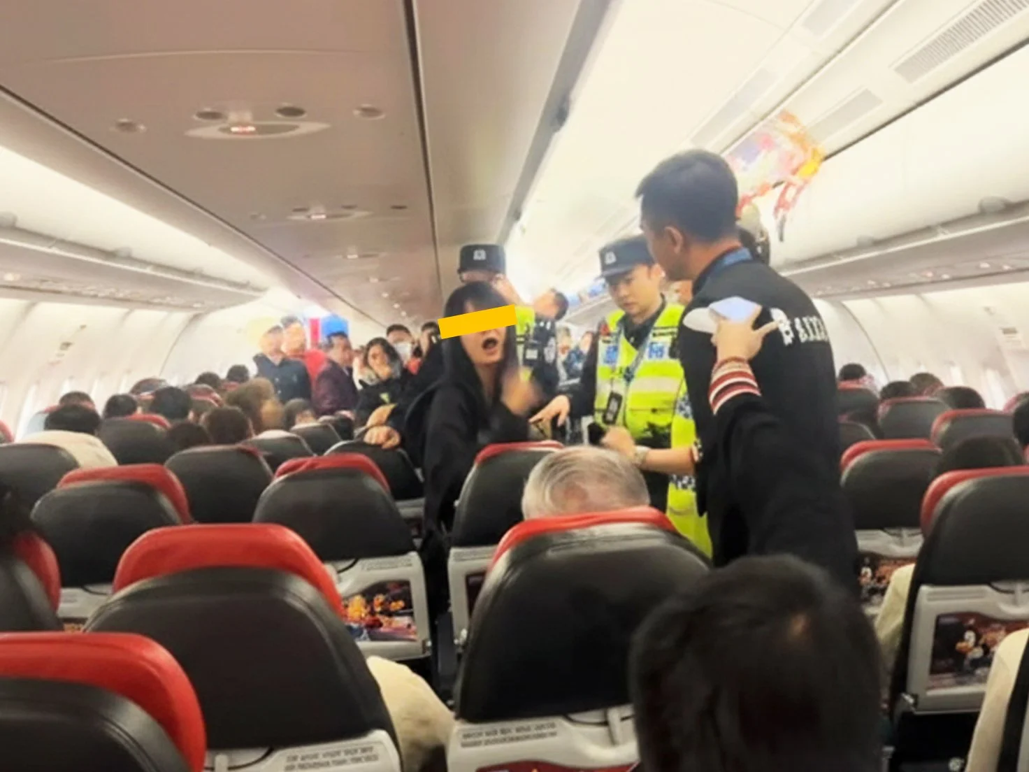 Flight crew managing a disruptive passenger on a plane, illustrating the implementation of an anti Karen travel policy.