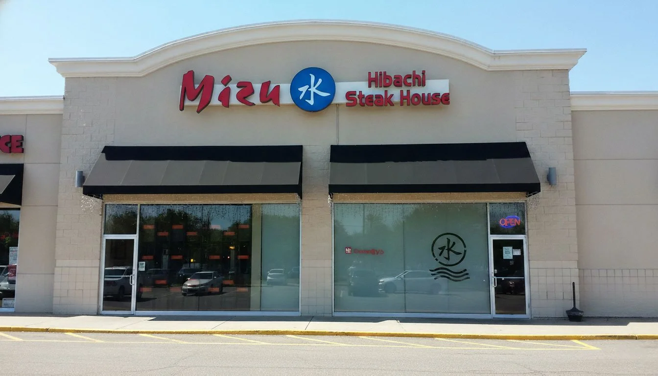 Daytime exterior view of the Mizu Hibachi Steak House storefront featuring black awnings and glass doors.