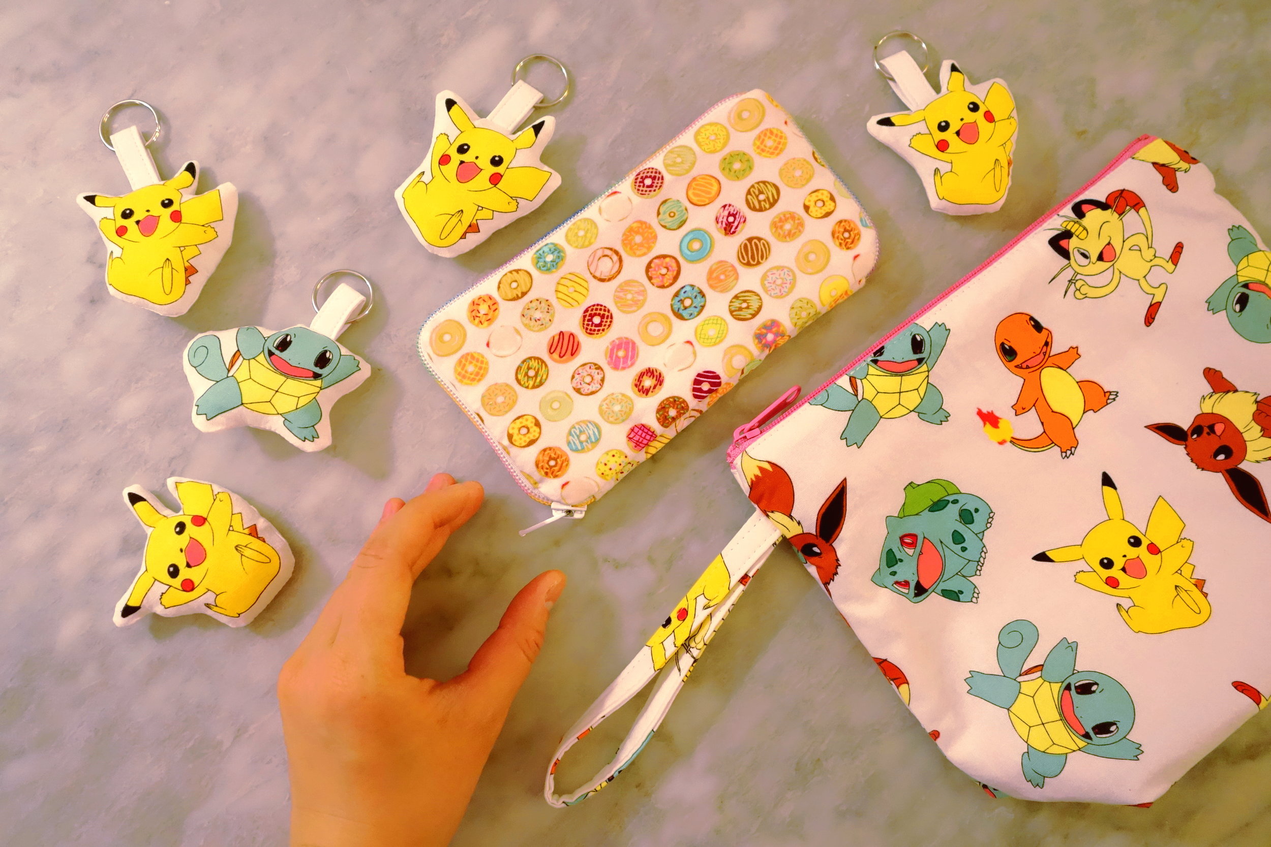 Donut Checkbook (Center), Pikachu Pillow (Bottom Left), Pokemon Pillow Keychains (Left & Top Right) & Pokemon Bag (Right)