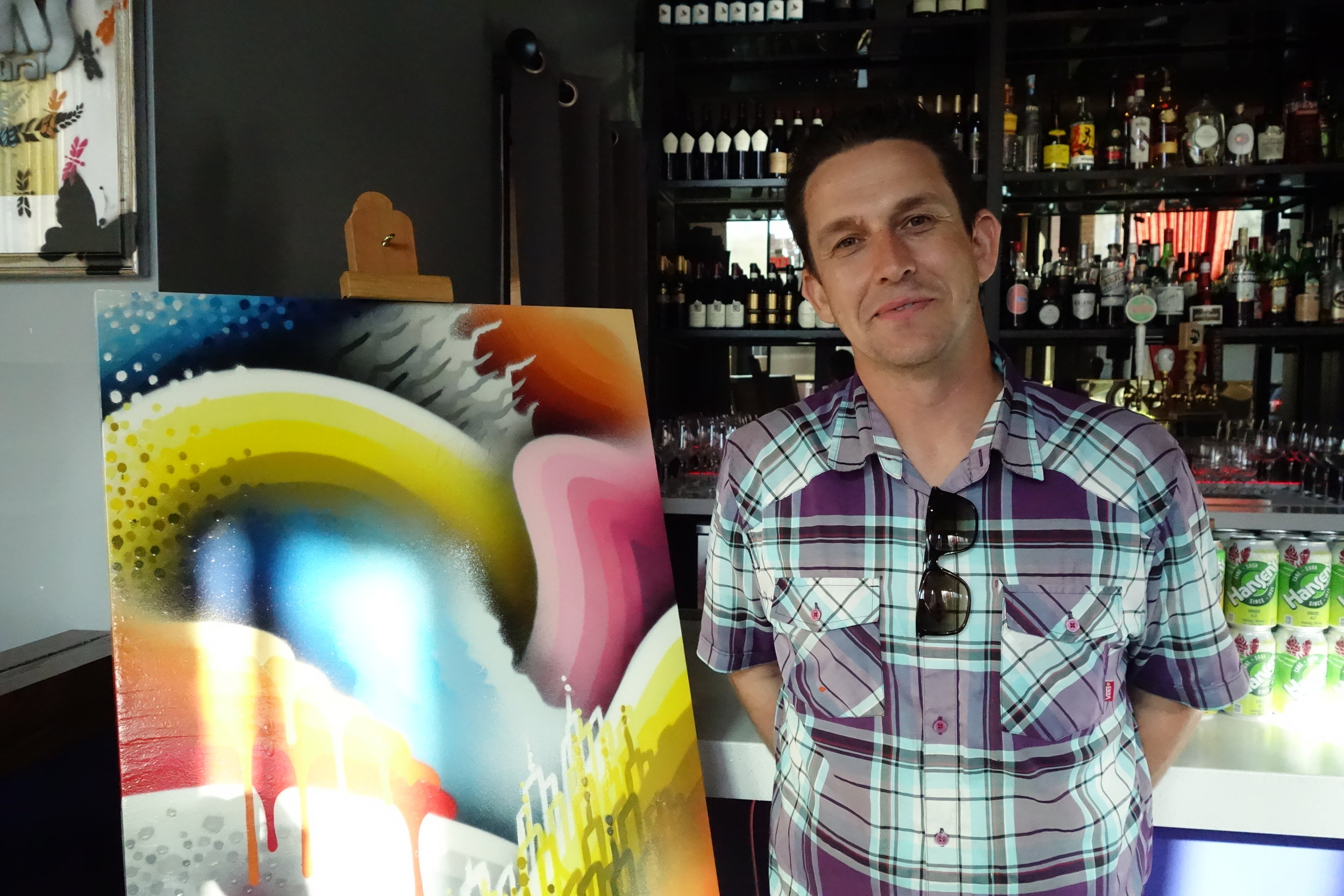 Local artist Ricky Watts poses in front of his artwork at Rooh SF in SoMa.