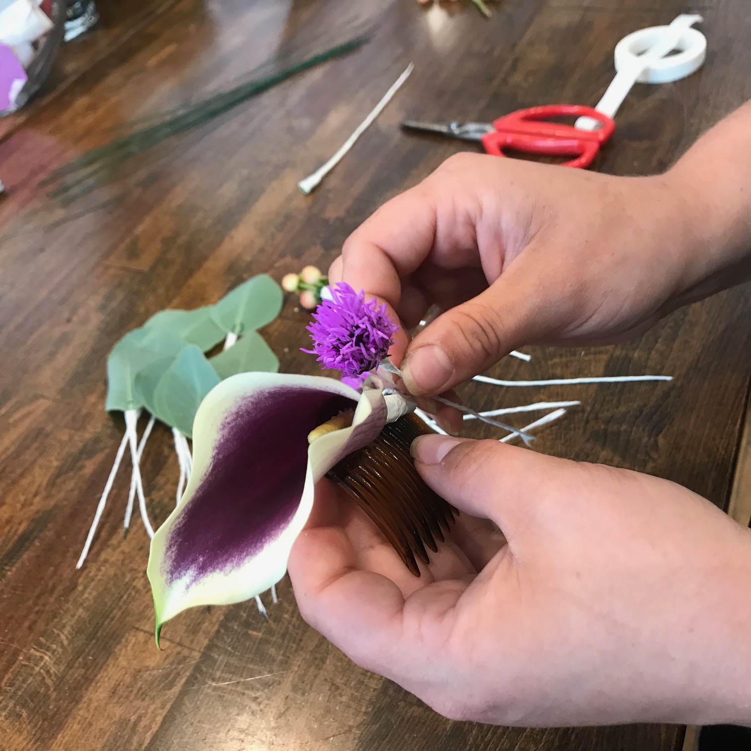  Step 3: Starting with the focal flower, layer the components ontop of one another, using the greenery to create volume. Wrap each "stem" between the teeth of the comb. 