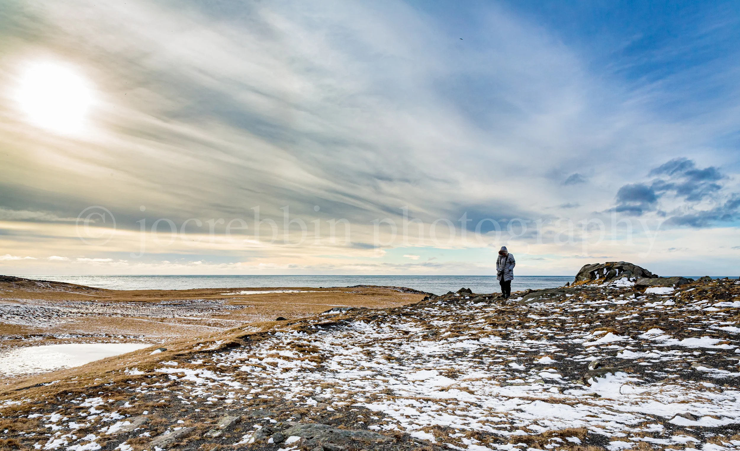 Visitor walks over lava rocks andd snow near Eystrahorn.jpg