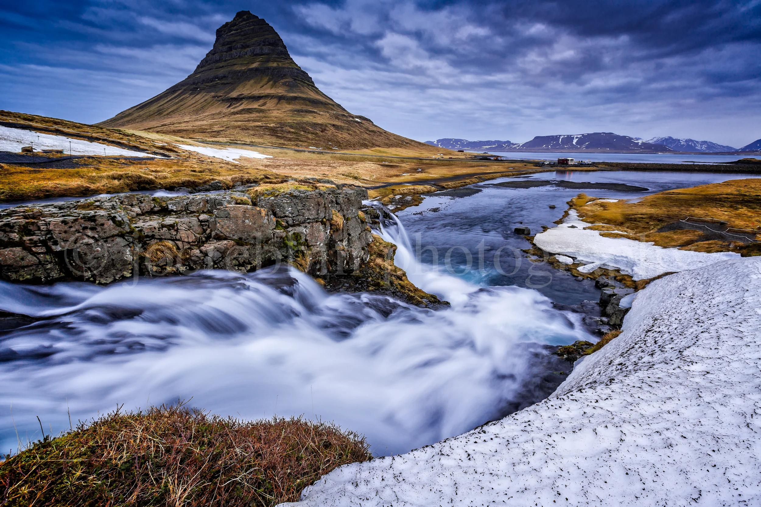 Mount Kirkjufell towers over rushing waterwalls in Iceland.jpg