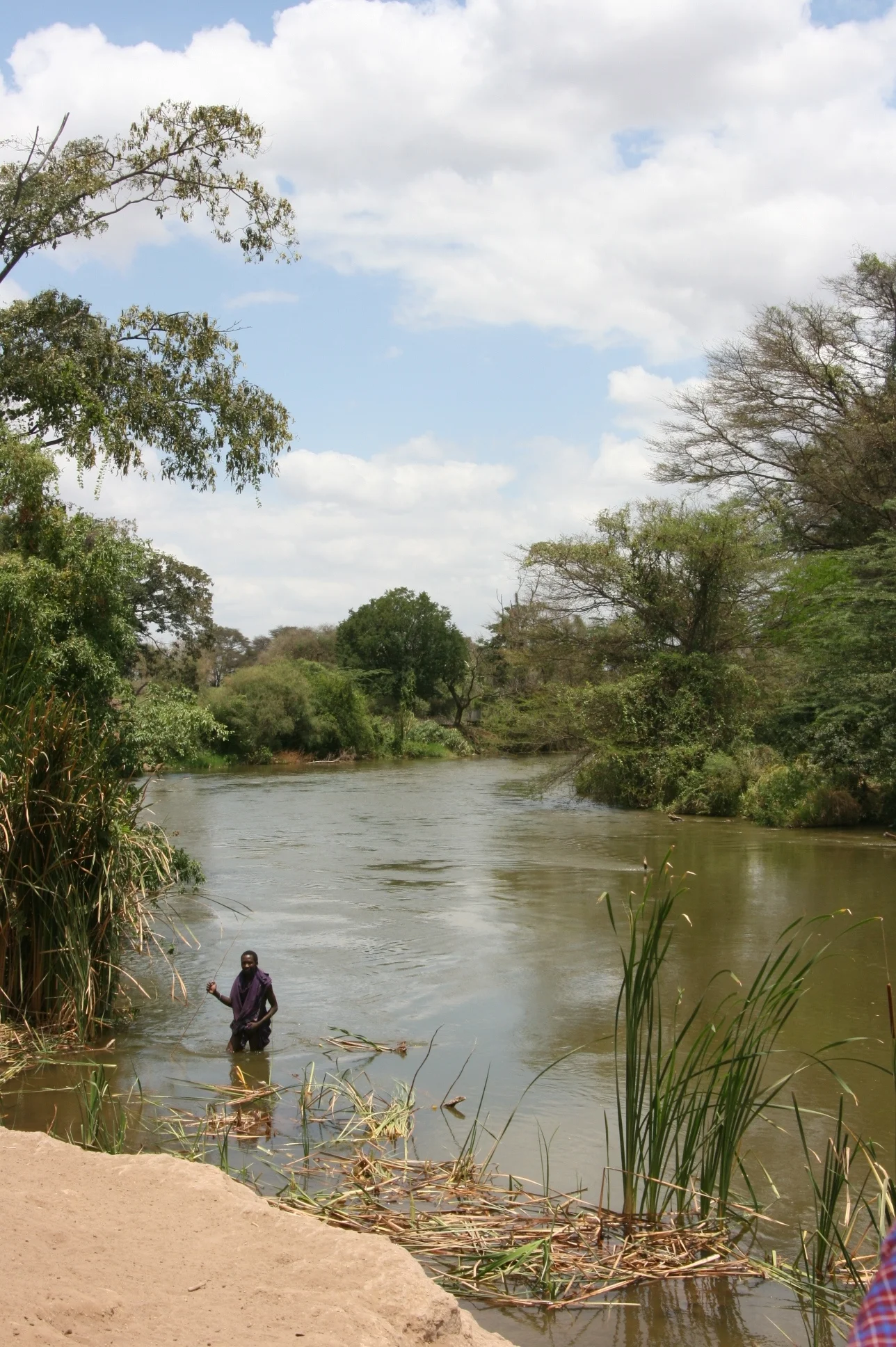 A man wades through the Pangani River while fishing - Tanzania