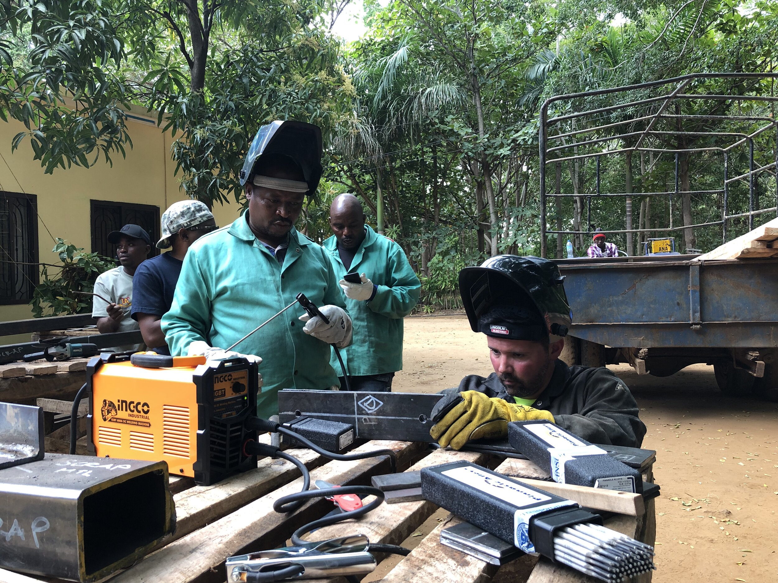 Mbesese build team member Ezekiel (left) and volunteer Rickey (right) prepare to begin welding