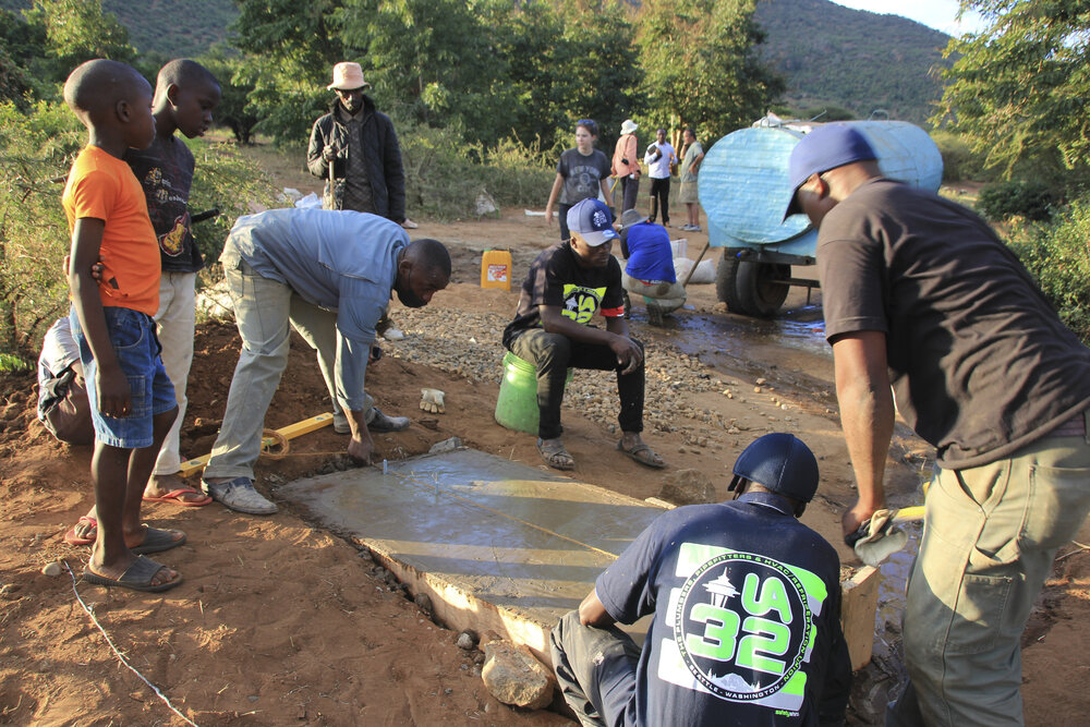 The Mbesese build team installs anchor bolts into one of the new foundations