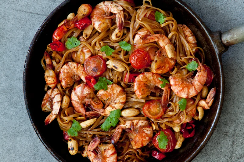 Oppskriften på stekte risnudler med scampi finner du på side 81 i boka LavFODMAP - Magevennlig Mat. Ønsker du å krydre den enda litt mer kan du tilsette for eksempel gulerot, chili, paprika eller mer ingefær. Foto: Magevennlig mat / Espen Døhlen