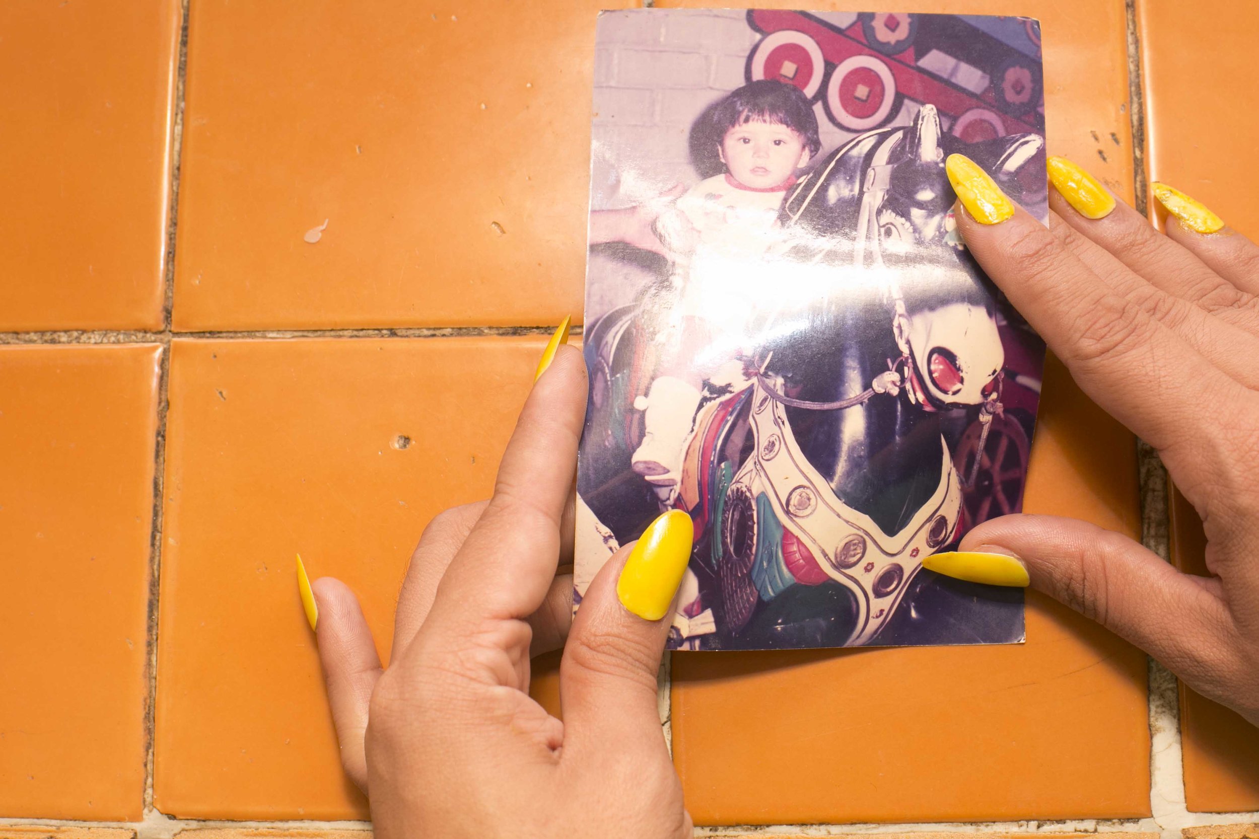 NadiA was kidnapped by her father at age three. This is one of the last photographs she has with her mother. She feels a huge hole in the space where her mother should have been which she is still trying to fill. She remembers crying on the floor listening to Gloria Trevi’s El recuento de los daños (Recounting of the Damages) while holding this image. It's painful to remember that time with her mother and to see herself dressed in boy’s clothes.